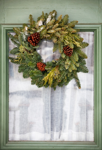 A nice evergreen wreath with a few small pinecones. Loving the color of that door, too!