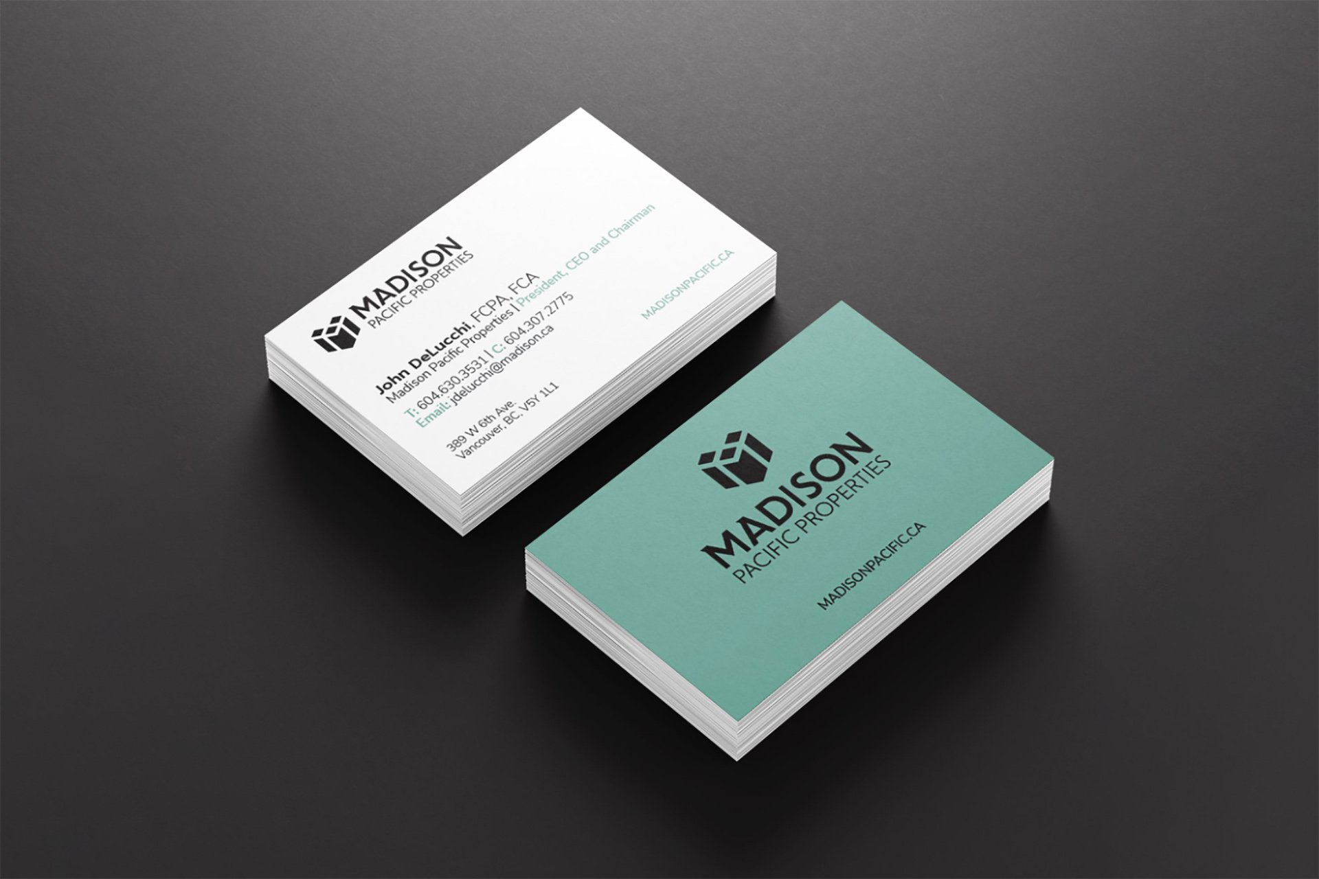 Stack of business cards for Madison Pacific Properties on a dark surface, showing different sides with logo and contact information.