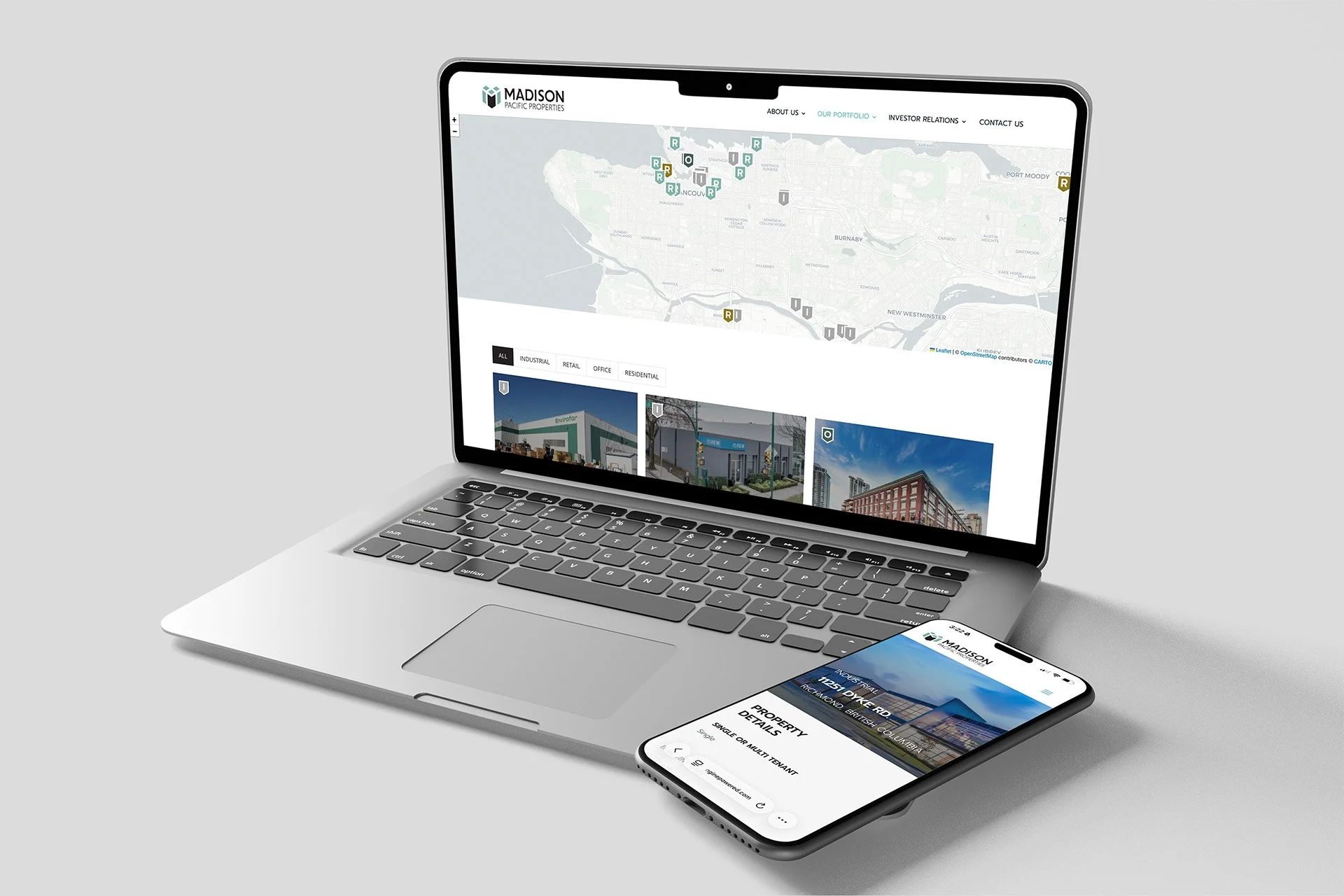 A silver laptop displaying a real estate website with a map and property images, and a smartphone showing the same website with property details.