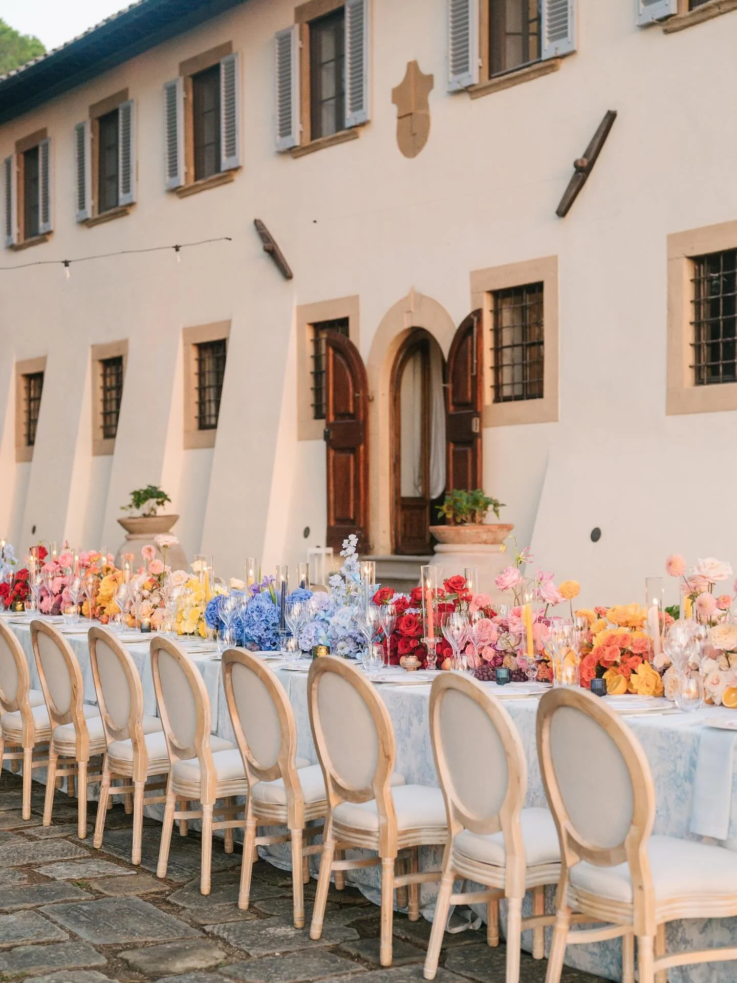 An imperial wedding table at @tenutasticciano for Nicola and David, a symphony of colors, from sapphire blues to sunset oranges and blush pinks, glowing beneath Tuscan lights. 

Wp: @paolocicognani_weddingsitaly 
Photographer: @landvphotography 
Vide