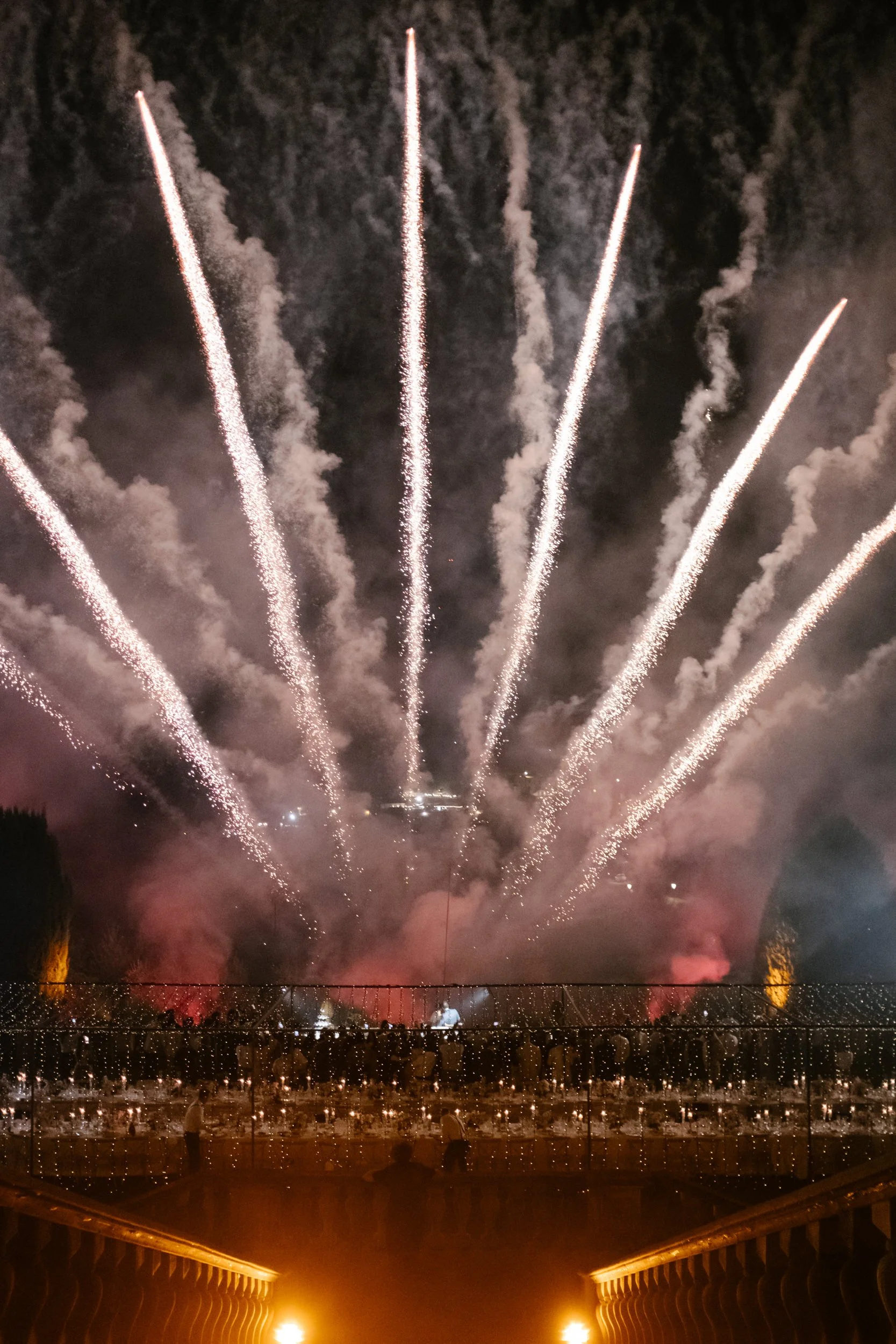 Fireworks display in the night sky with multiple bright streaks and smoke.