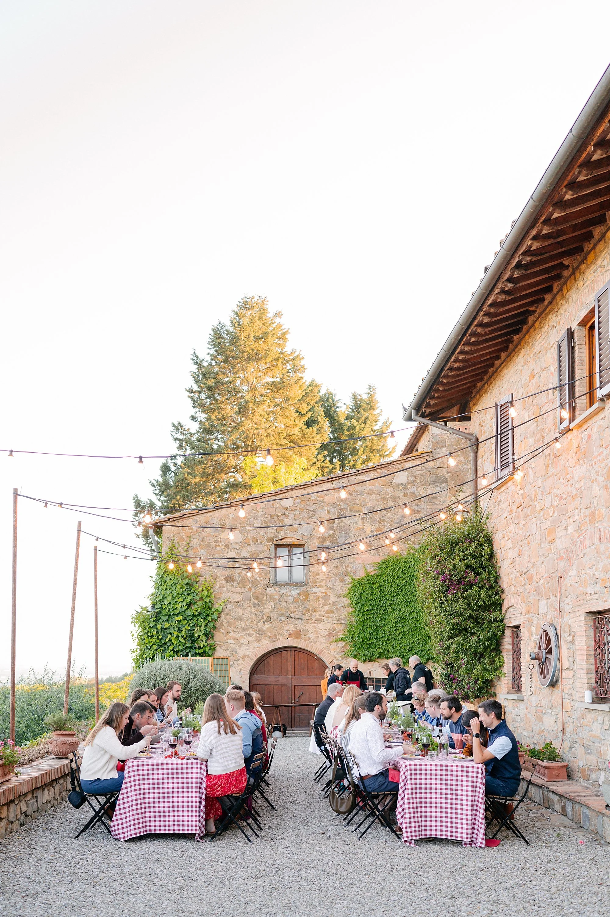 Candid wedding welcome party photography in Italy, guests enjoying pizza and tuscan wines at sunset.