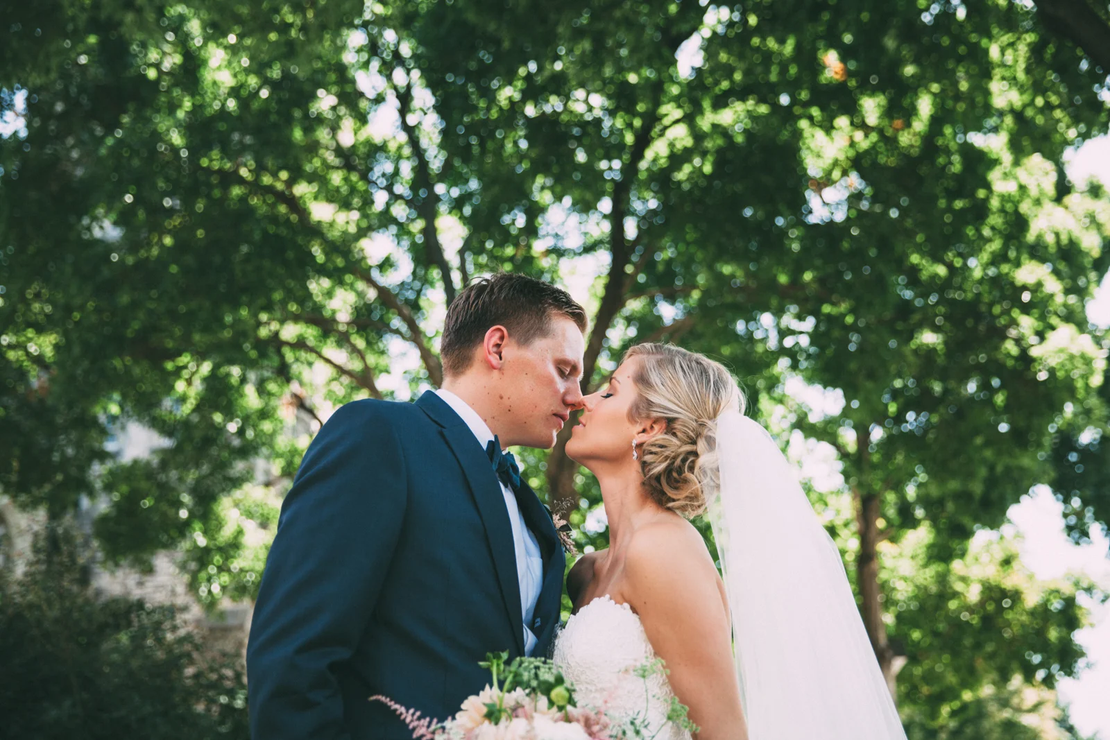 Bride and Groom kissing under trees