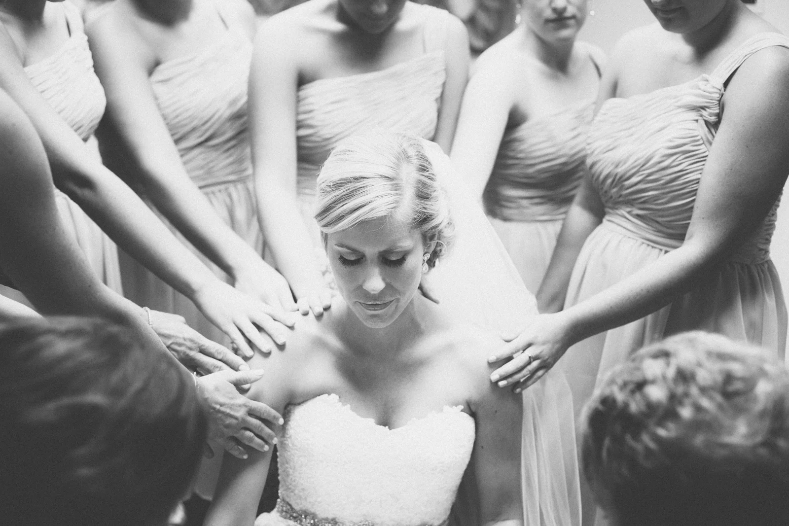 Bridesmaids pray over the bride before the wedding ceremony