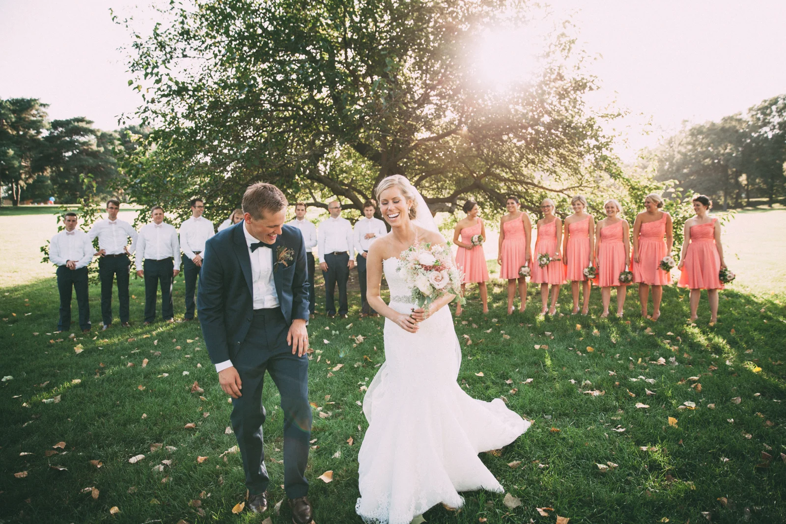 Bride and groom laughing with wedding party in the country