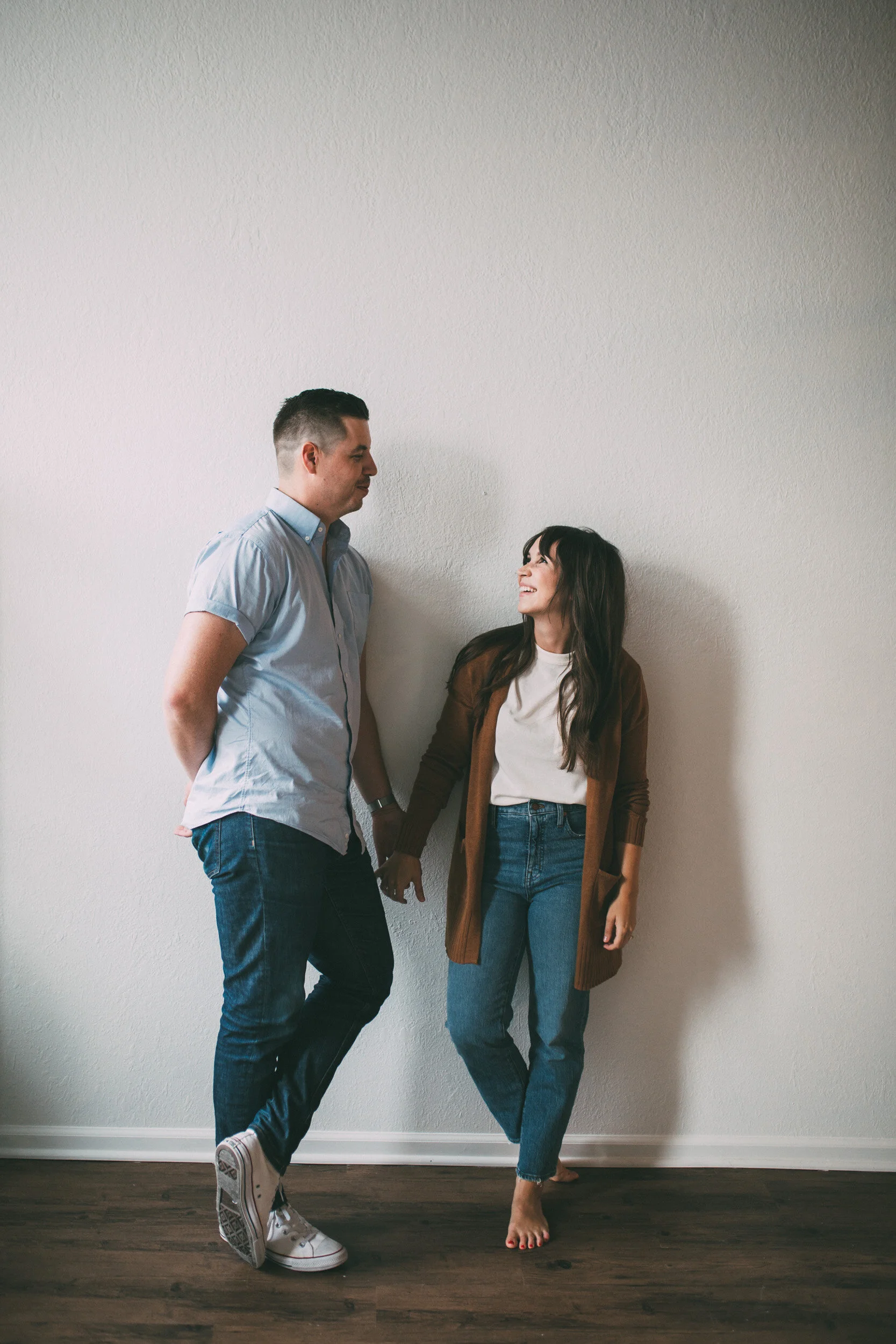 couple standing against white wall smiling