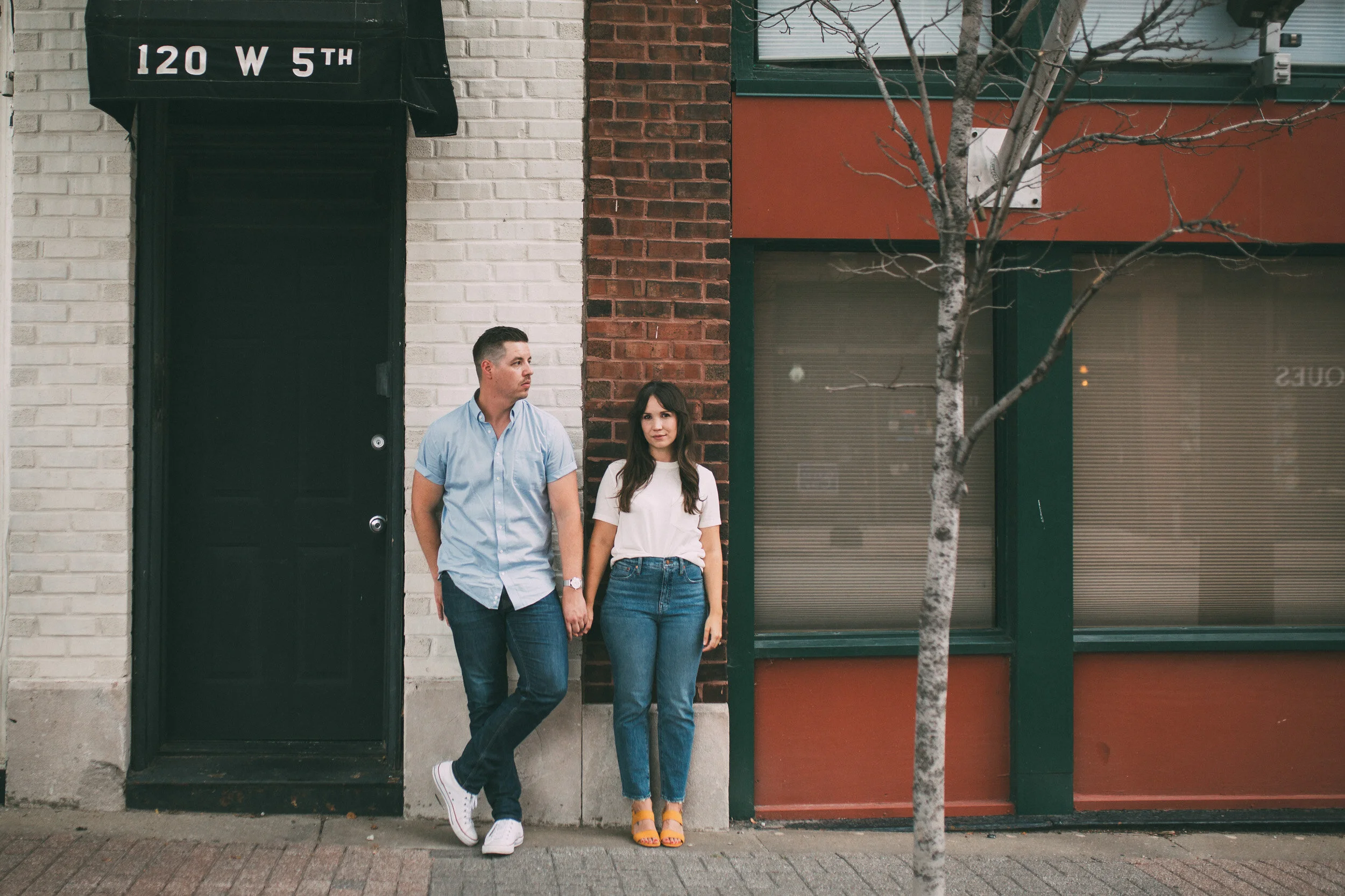 engagement photo on city street in front of brick storefront