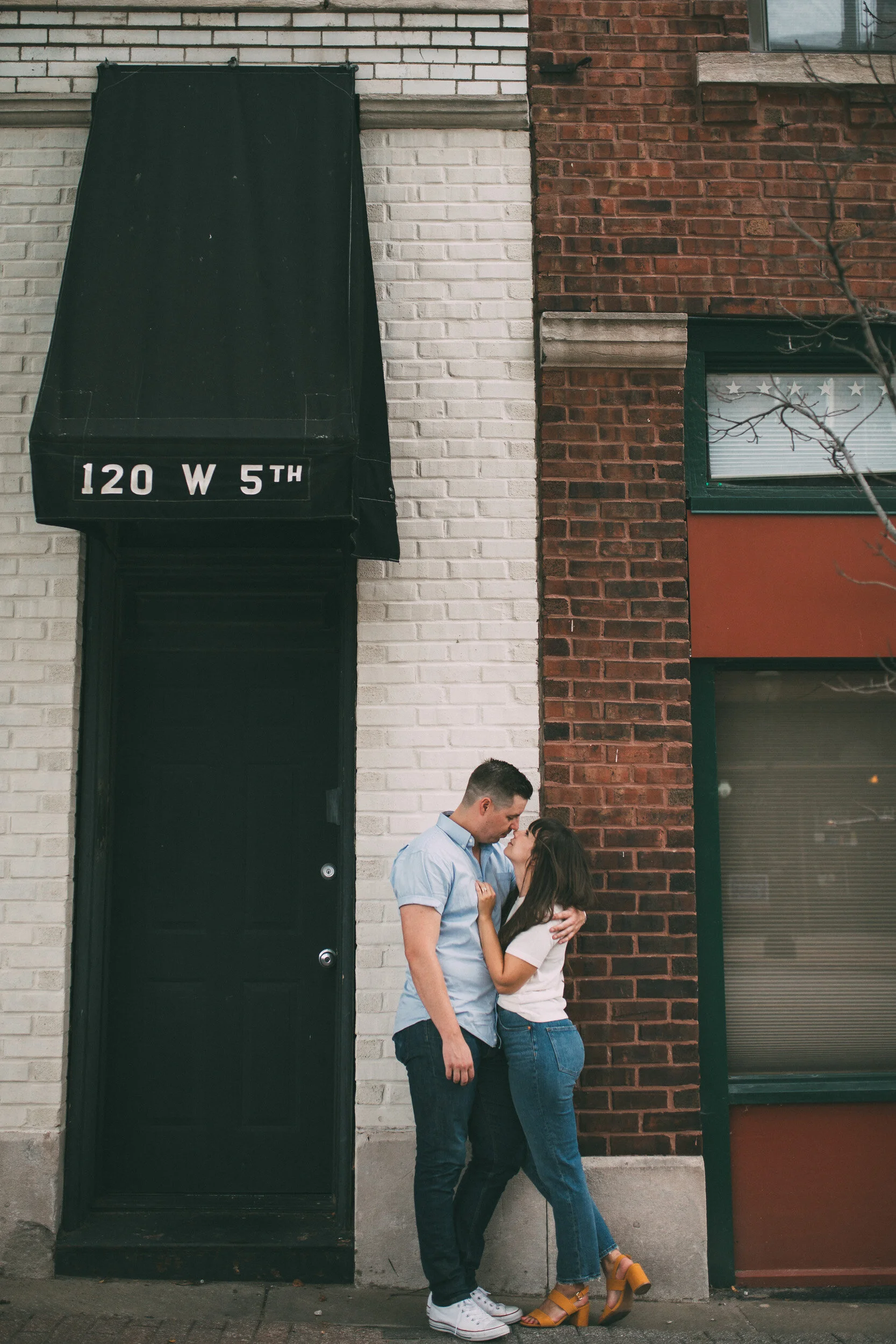 engagement photo on city street in front of brick storefront