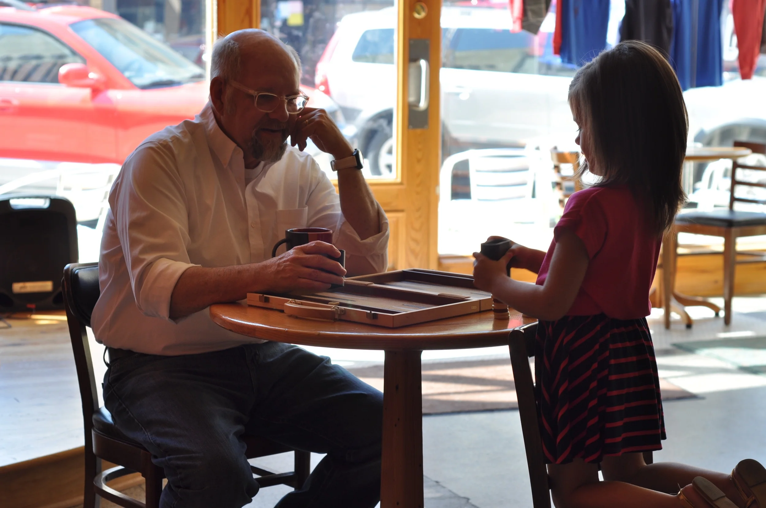 POPS AND KARLEE PLAYING SOME BACKGAMMON IN A COFFEE JOINT PERFECT FOR A BOOK DISCUSSION