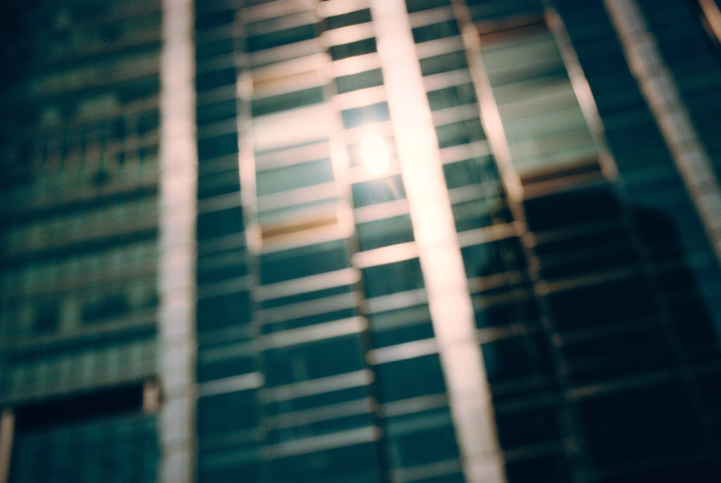 Close-up of a window with horizontal blinds, slightly open, with light filtering through.