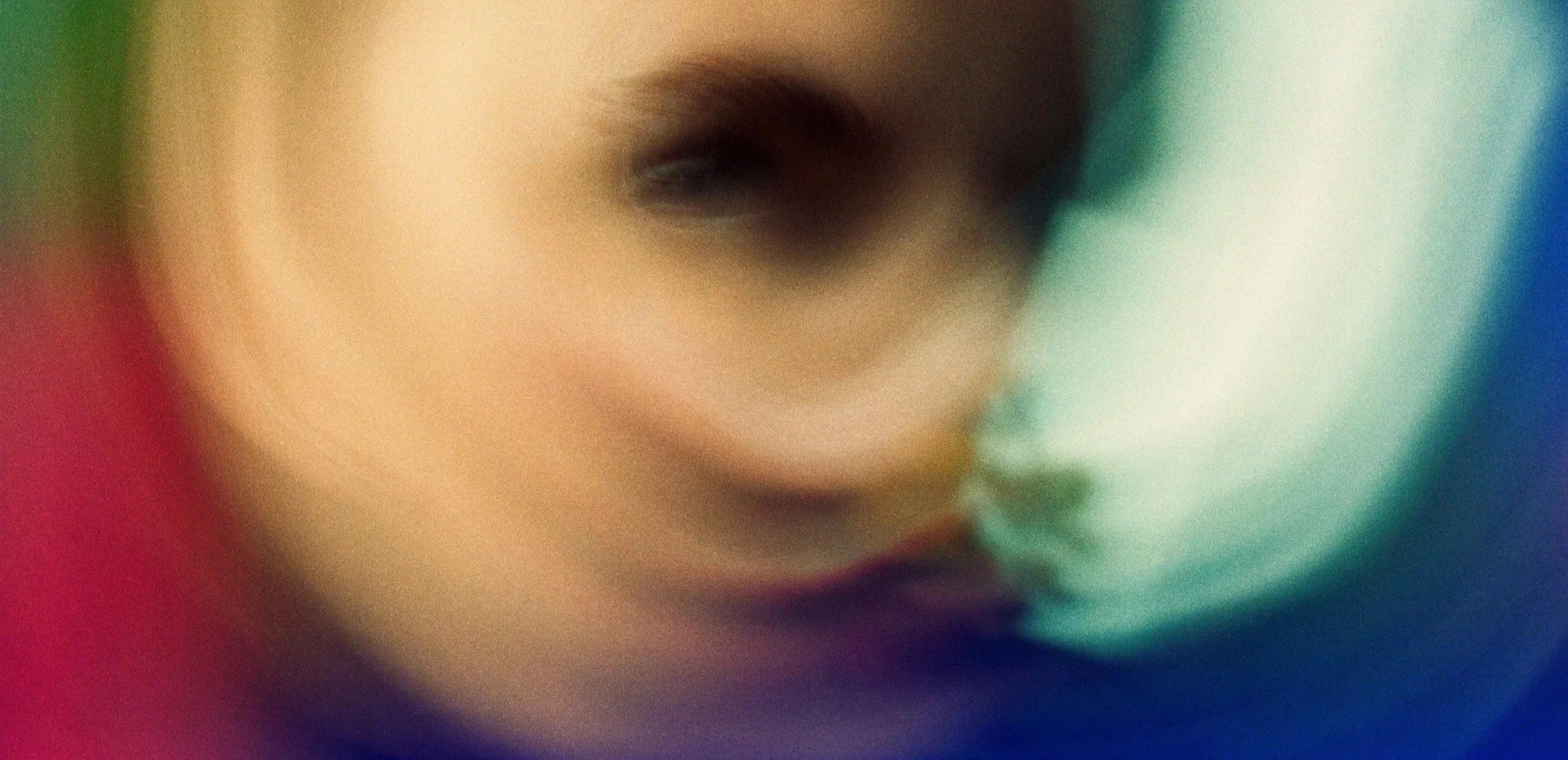 Close-up of a person's face with a blurred effect, showing a partial view of a nose and lips, with colorful background.