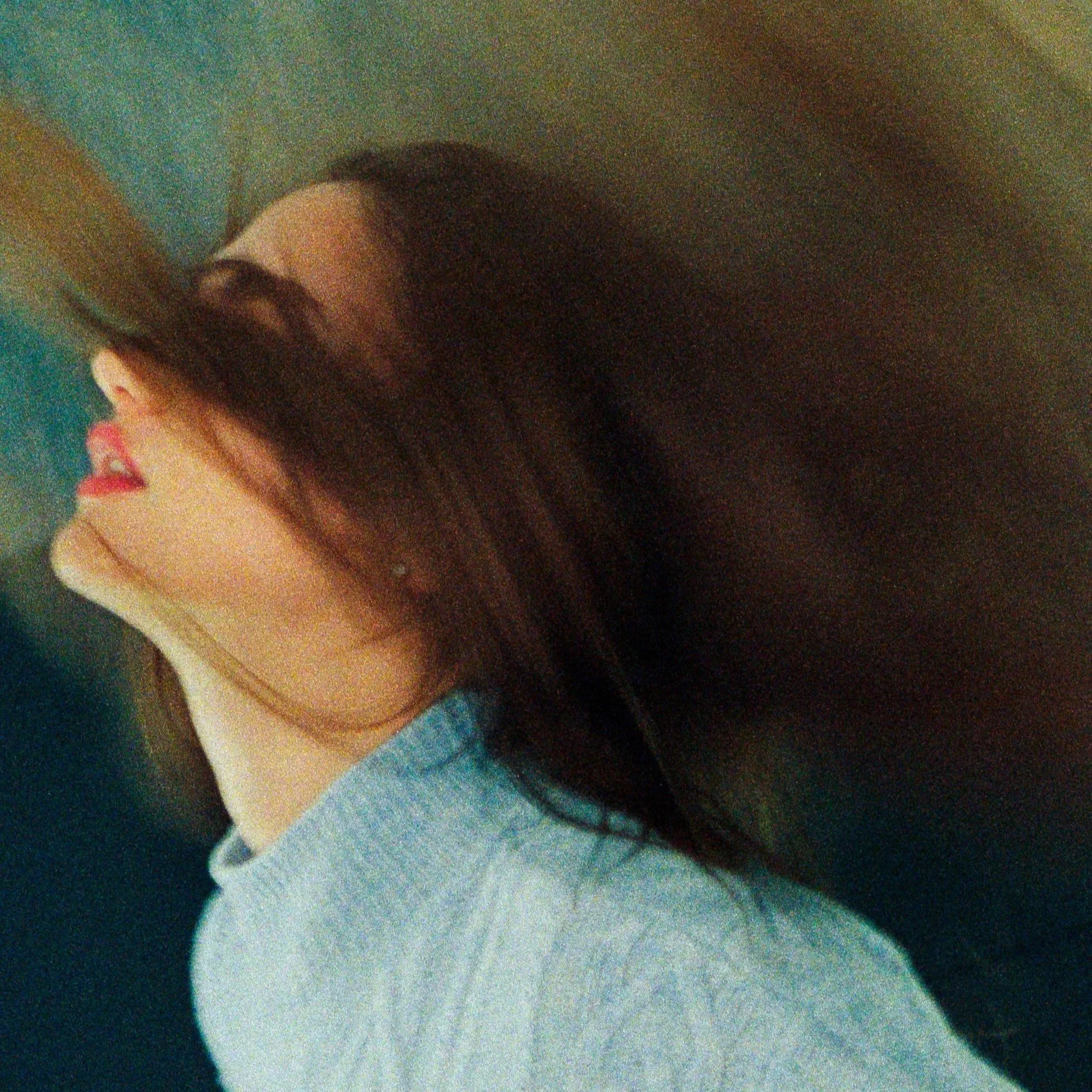 Close-up of a person with long dark hair, red lipstick, wearing a light-colored hoodie, and Voldemort from Harry Potter.