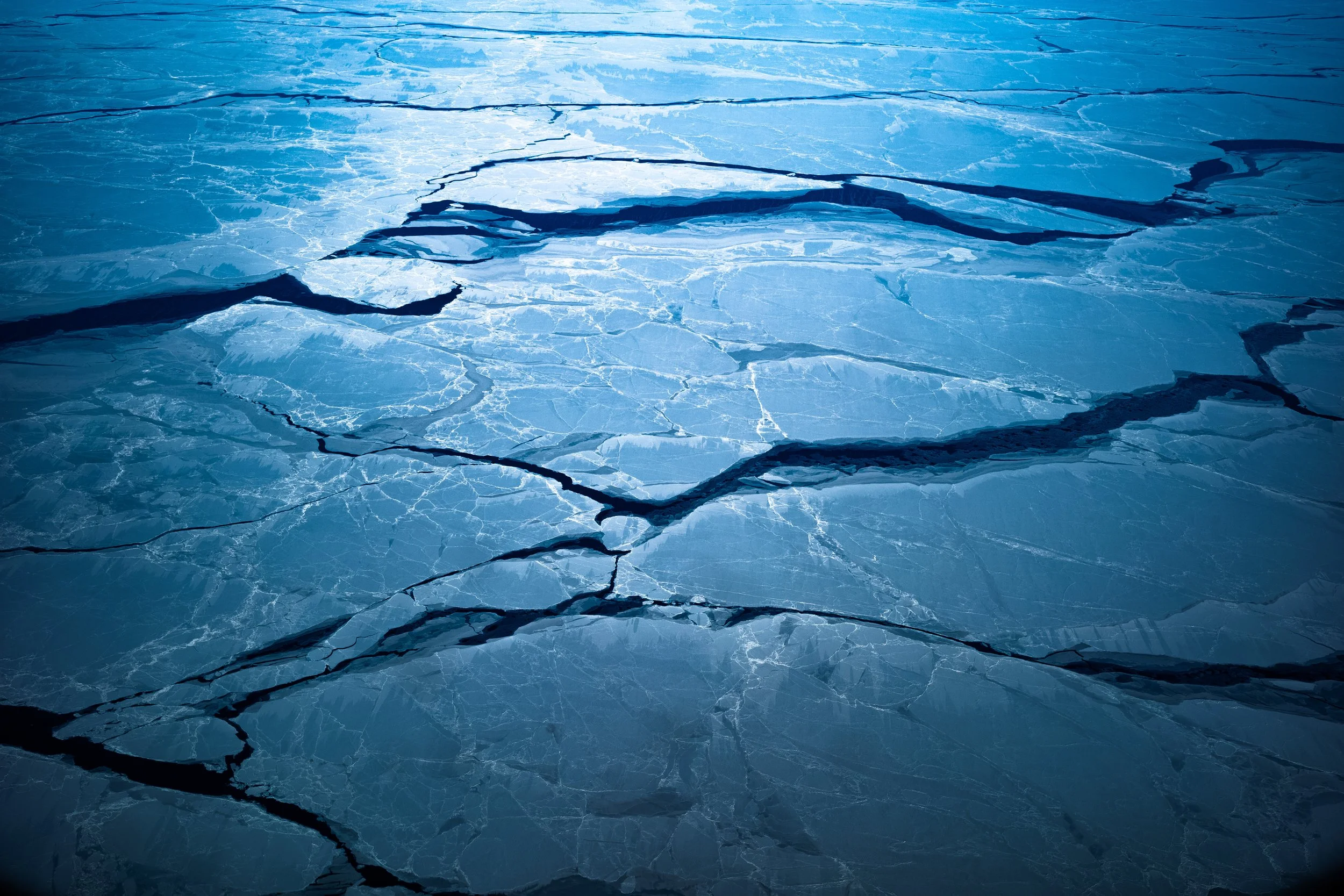 Frozen ice surface with visible cracks in a blue hue.