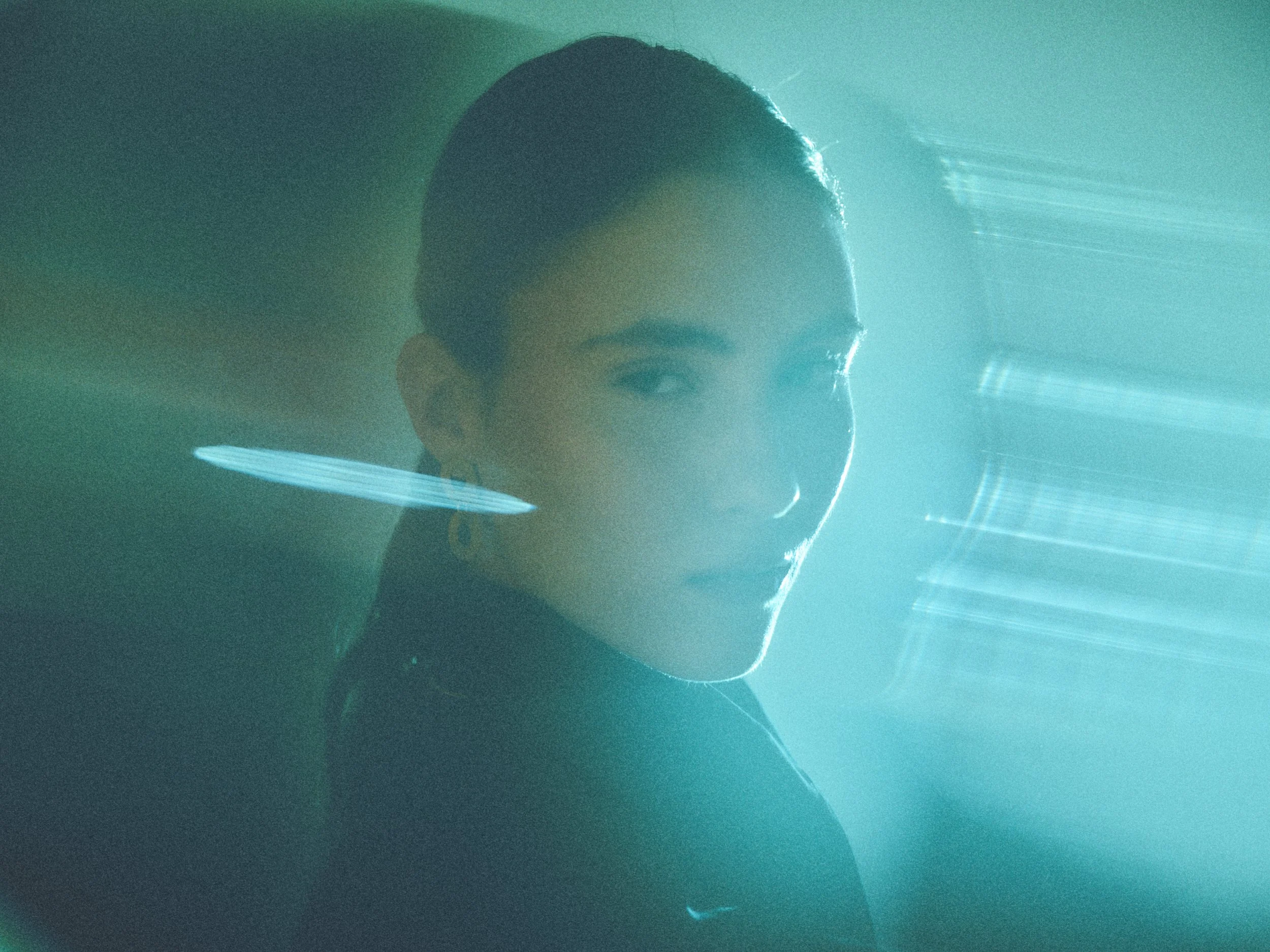 Close-up of a person's face, mostly obscured by a misty, turquoise light diffraction effect.
