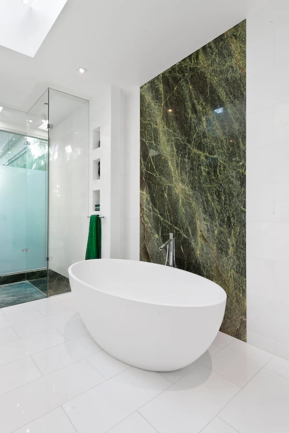 Bathroom with green stone feature wall and free standing bath.