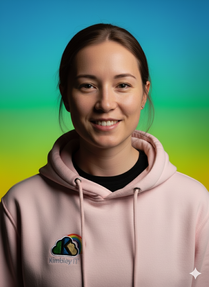 A young woman with brown hair wearing a pink hoodie with a 'Kimbley IT' logo and a rainbow, standing against a colorful gradient background.