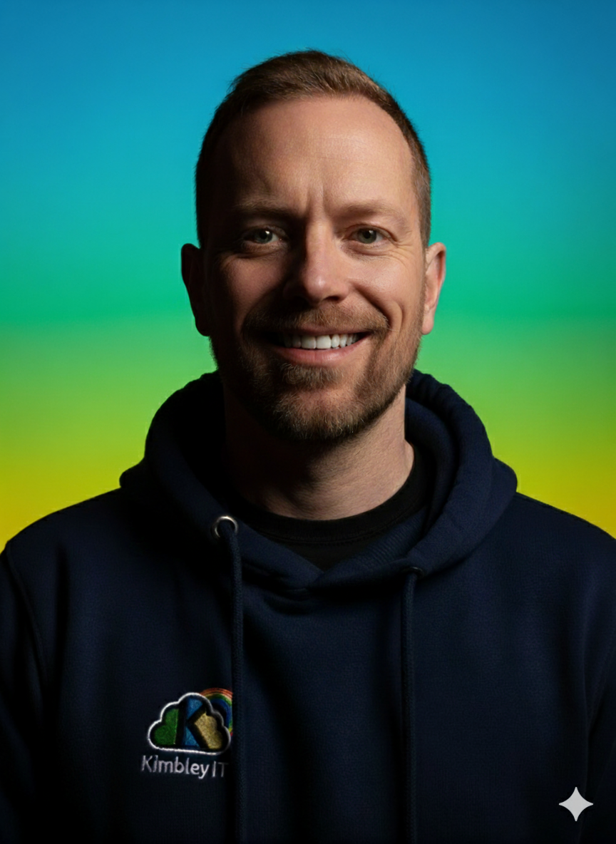 Smiling man with short hair and beard wearing a dark hoodie with Kimberly IT logo in front of a gradient background transitioning from blue to green.