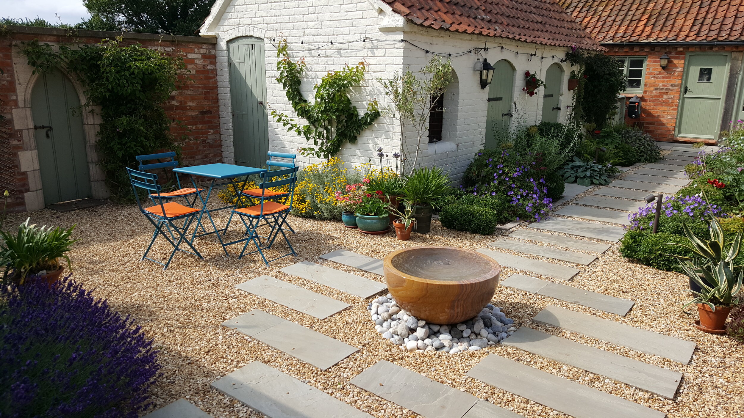 3 Garden design Lincolnshire - stepping stones gravel courtyard water feature and garden table.jpg