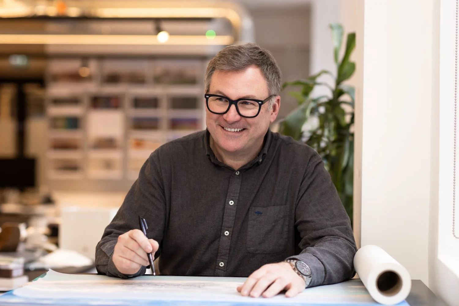  An architect in his studio sketches and pauses to smile  