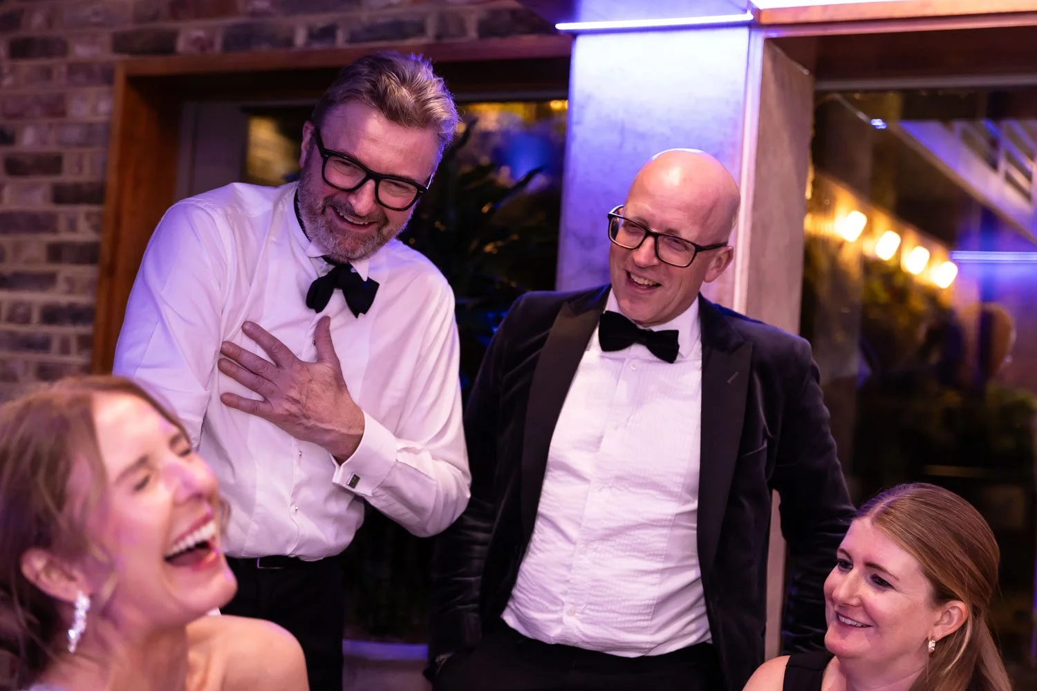  Guests laughing at a black tie dinner party event 
