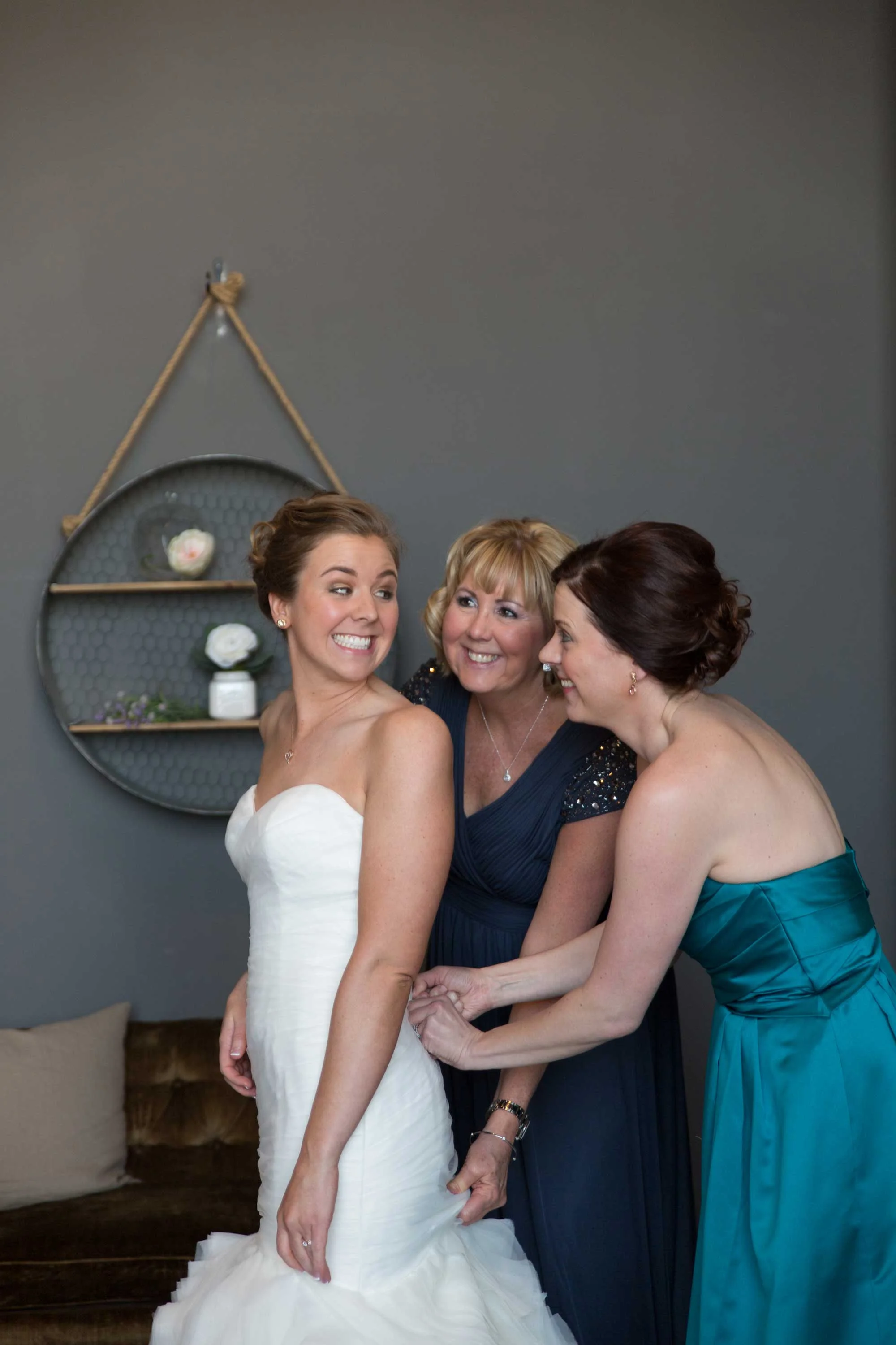 3. ALL SMILES AS OUR BRIDE'S MOM & MAID OF HONOR LACES UP HER DRESS.