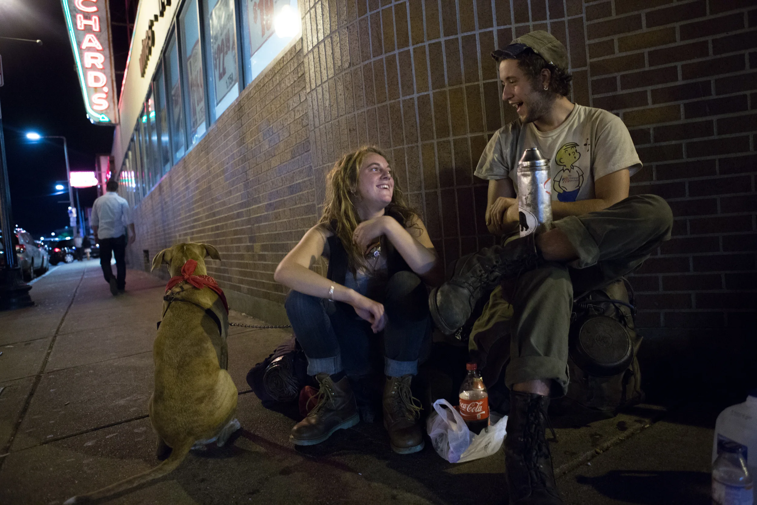 Two homeless 20-year-olds who asked to be identified as Toby (left) and Anchor (right) sit outside Blanchard's liquor store in Allston where they asked pedestrians for money and alcohol with their dog, Venus. The couple had recently traveled from Colorado by hitching rides on cargo trains. Photo credit: Justin Saglio