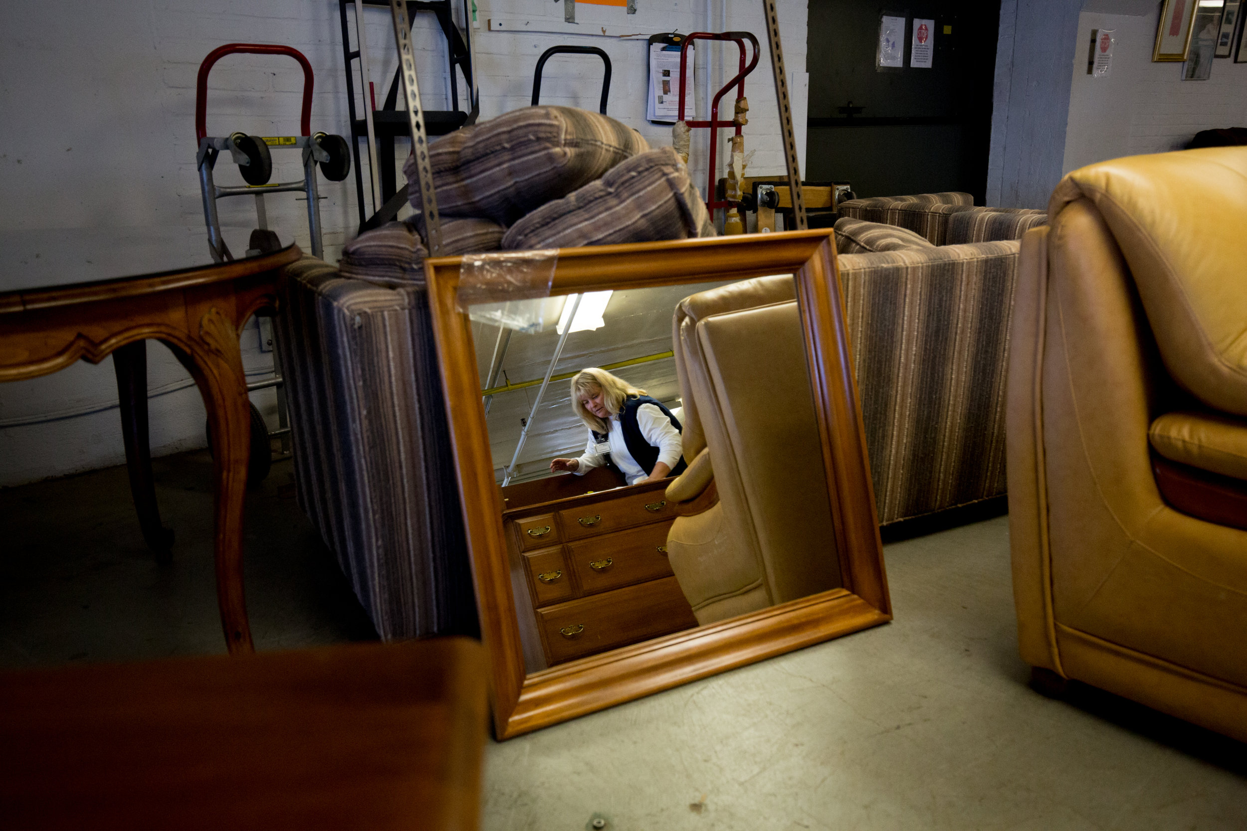 Nov. 25, 2017 - Renee LeBlanc is reflected while cleaning a dresser at New Life Bank Furniture in Walpole, Mass., which provides furniture to families in need.
