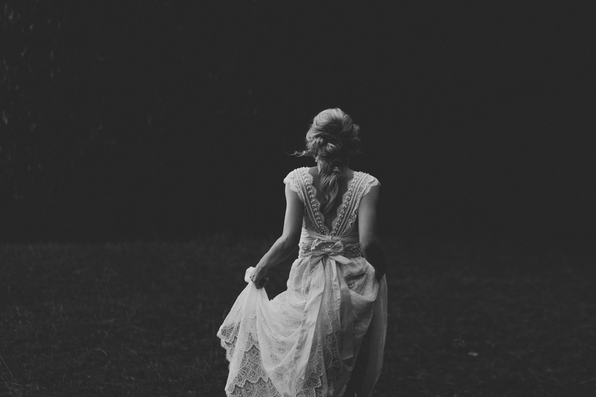 Bride walking through field in an Anna Campbell wedding dress provided by Wildflower Bridal in Asheville, NC. 