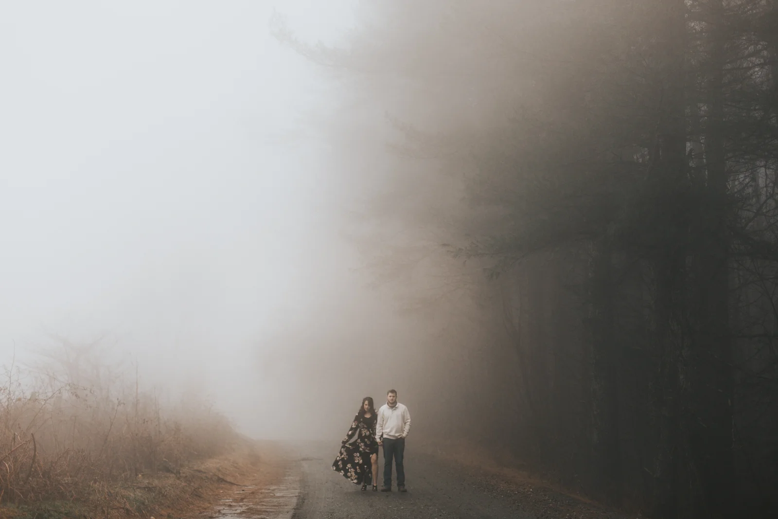 Couple walking down a gravel road on Max Patch mountain in the fog. 