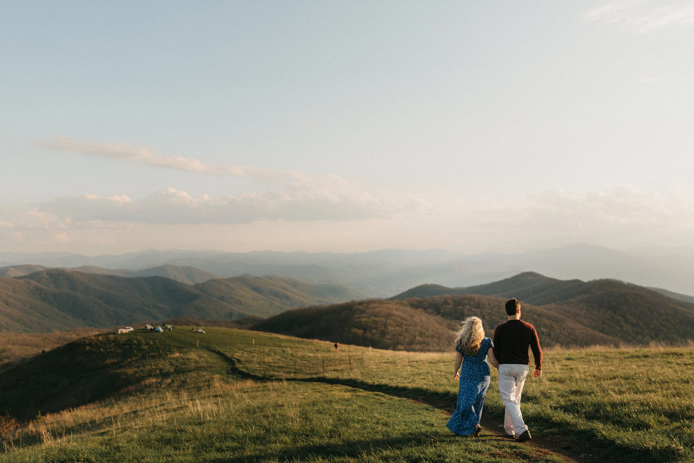 Couple walking along the Appalachian trail at sunset on Max Patch Mountain. 