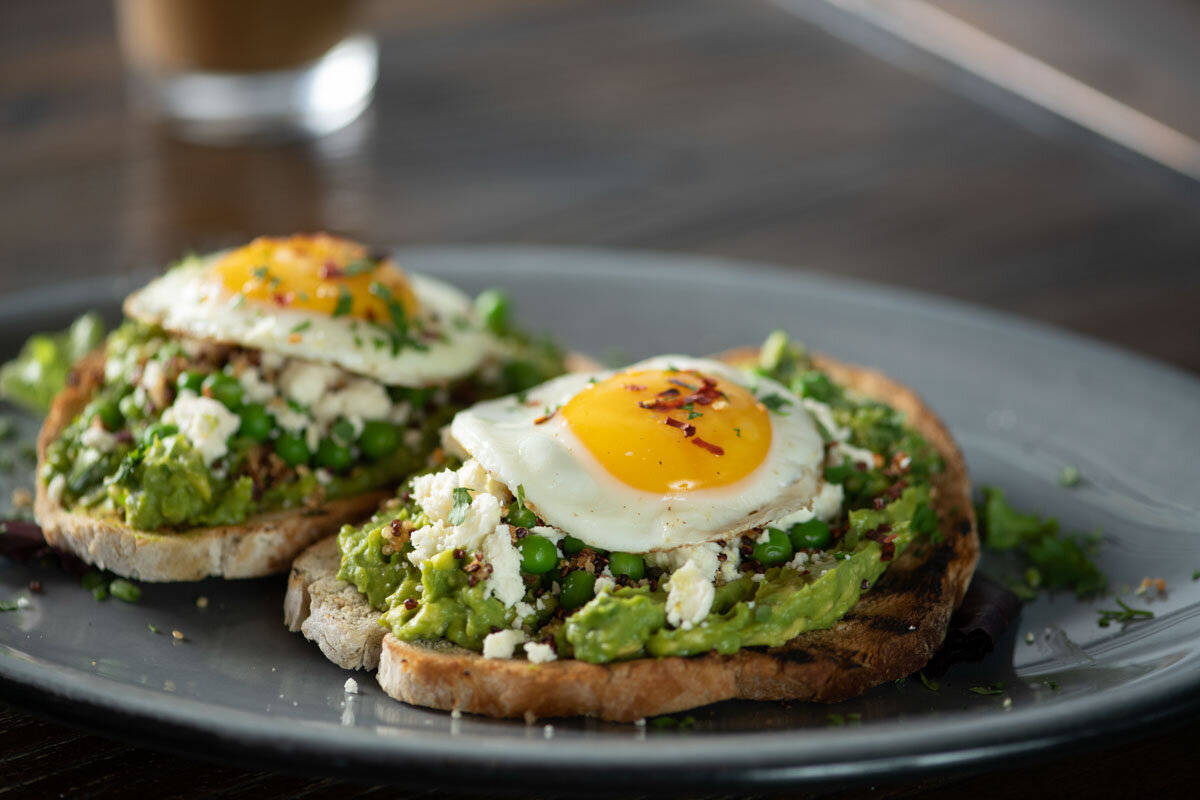 Two slices of rustic avocodo toast topped with a fried egg