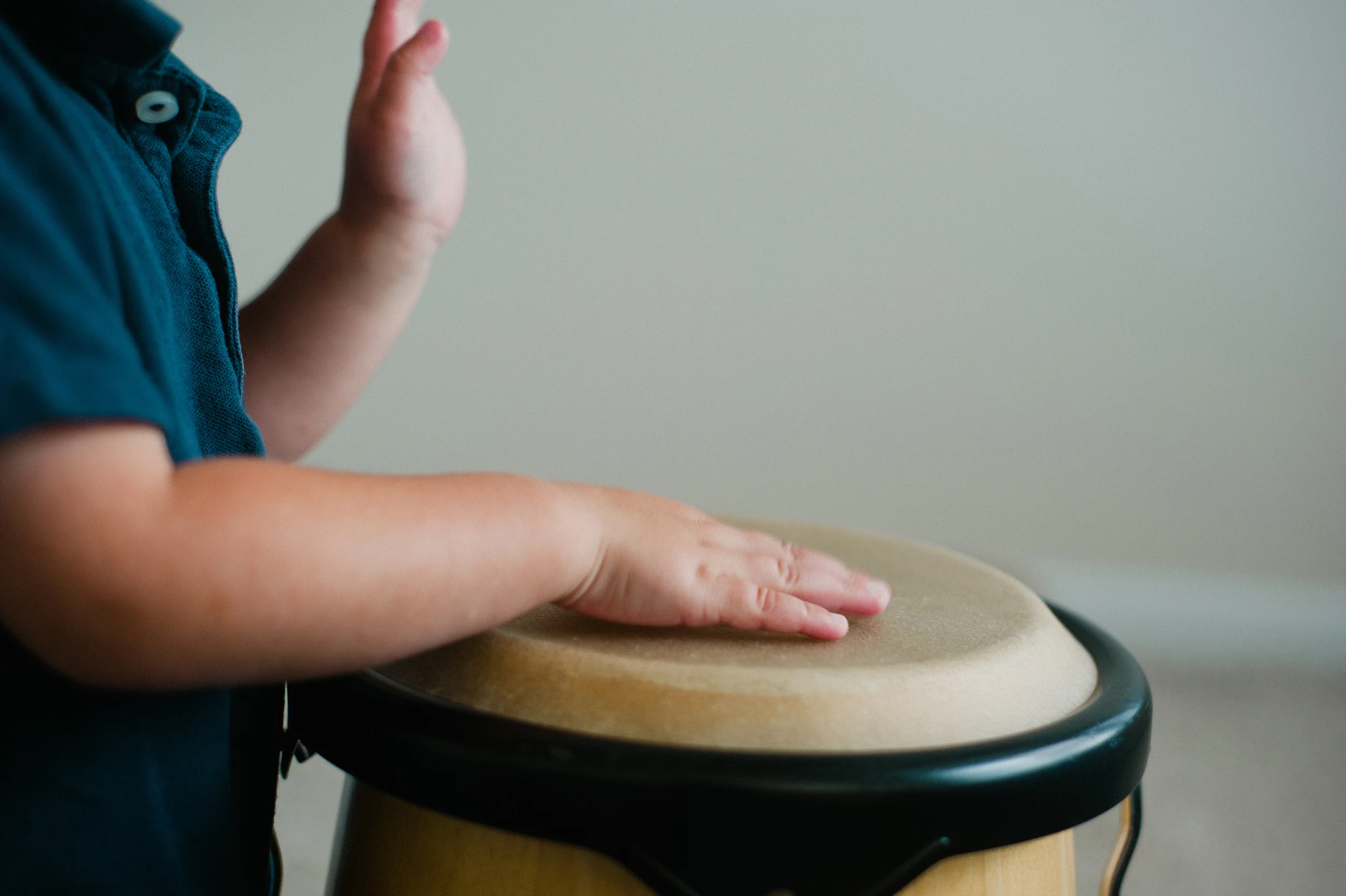 Child playing a bongo drum.