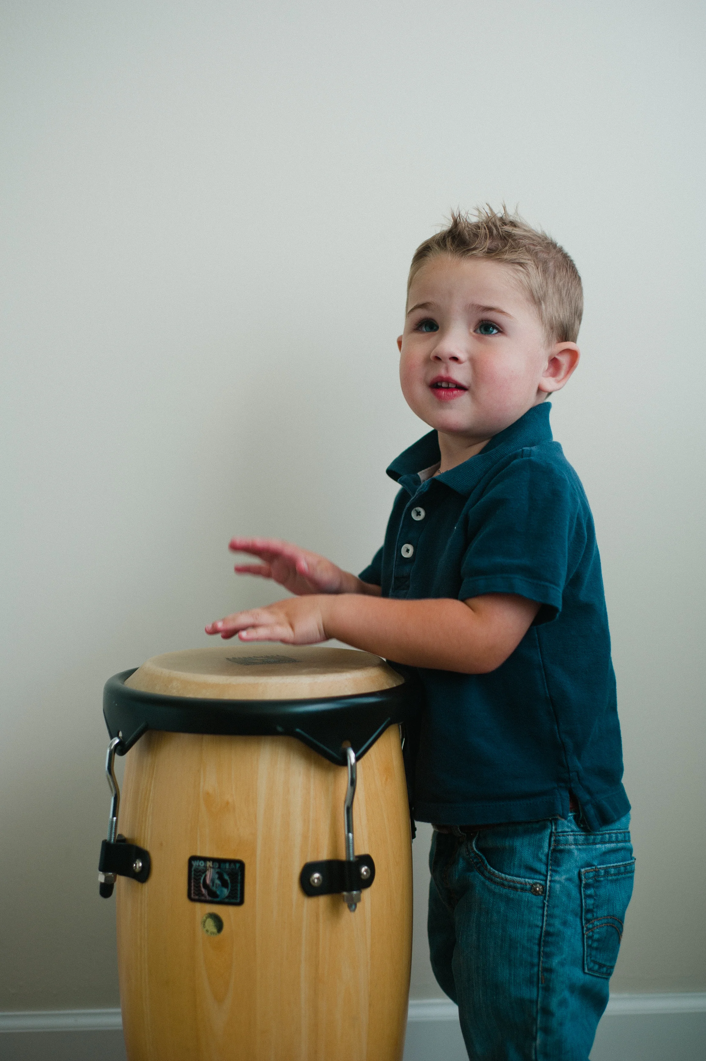 Young child playing a conga drum indoors.