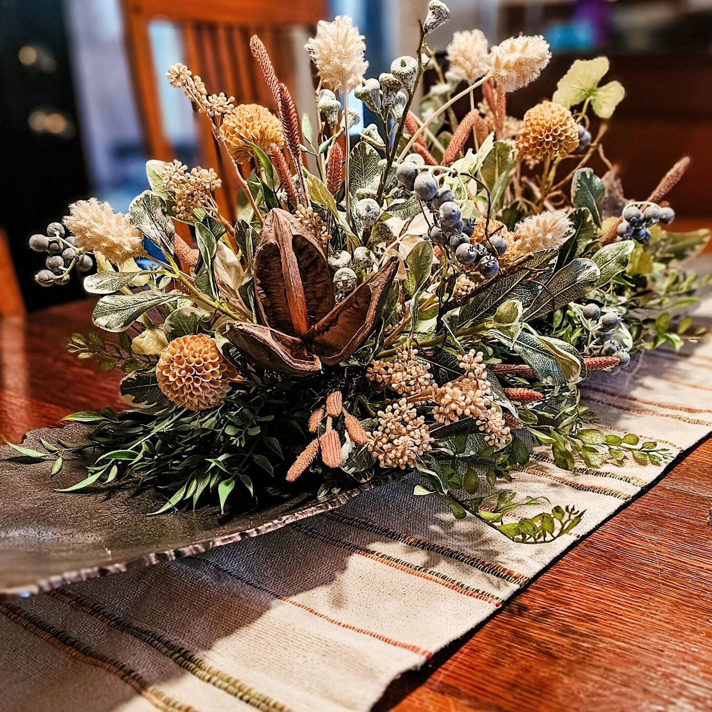 Beautiful custom floral for a client's dining room table with stunning uber long Uttermost pewter tray as vessel with nubby linen runner. #chicagointeriorstylist #procurement #shopping #customflorals #accessorizing #homeaccents #driedflowers #silkflo