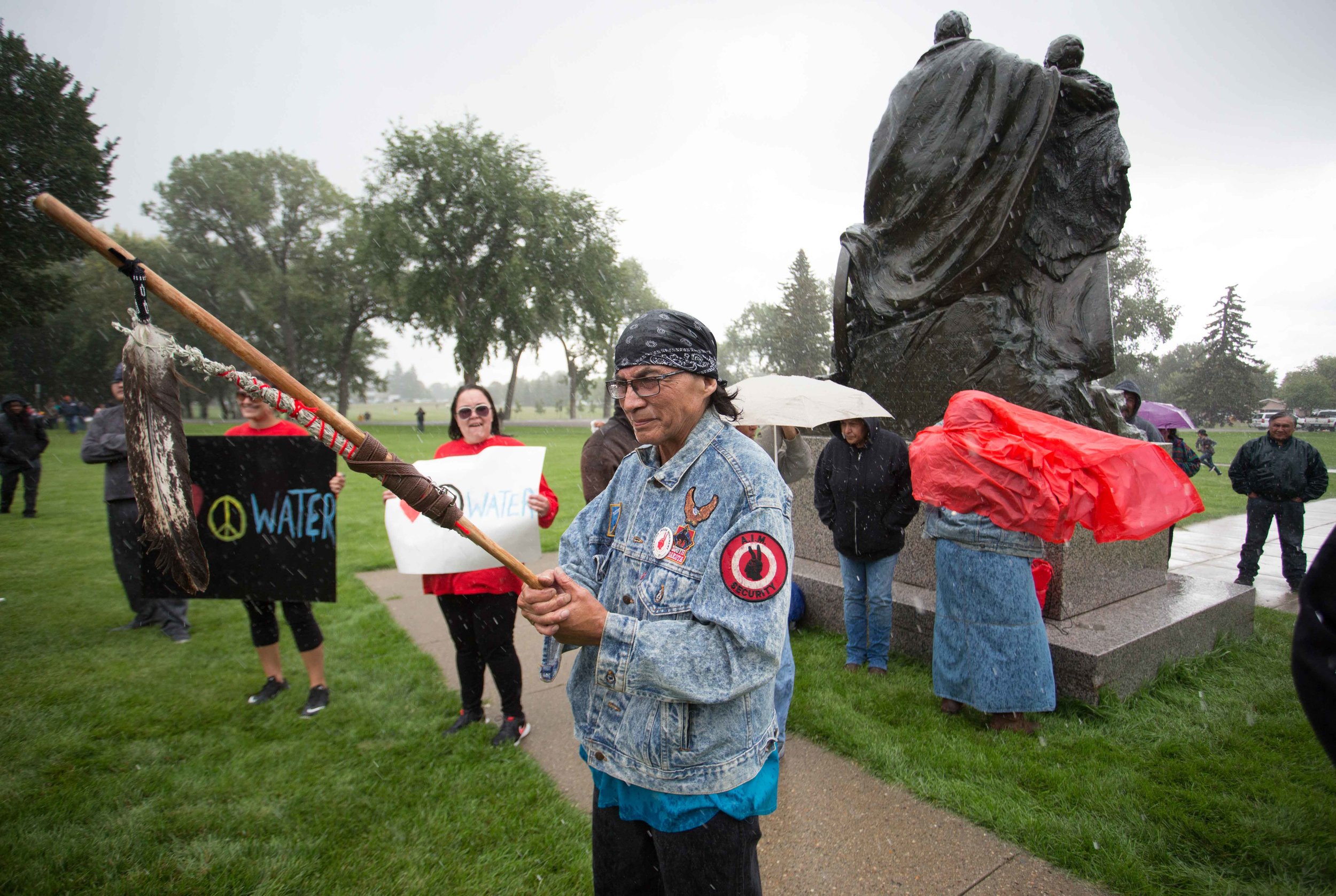  A protetster holds a ceremonial staff while protesting the Dakota Access Pipeline in front of the state capitol. 