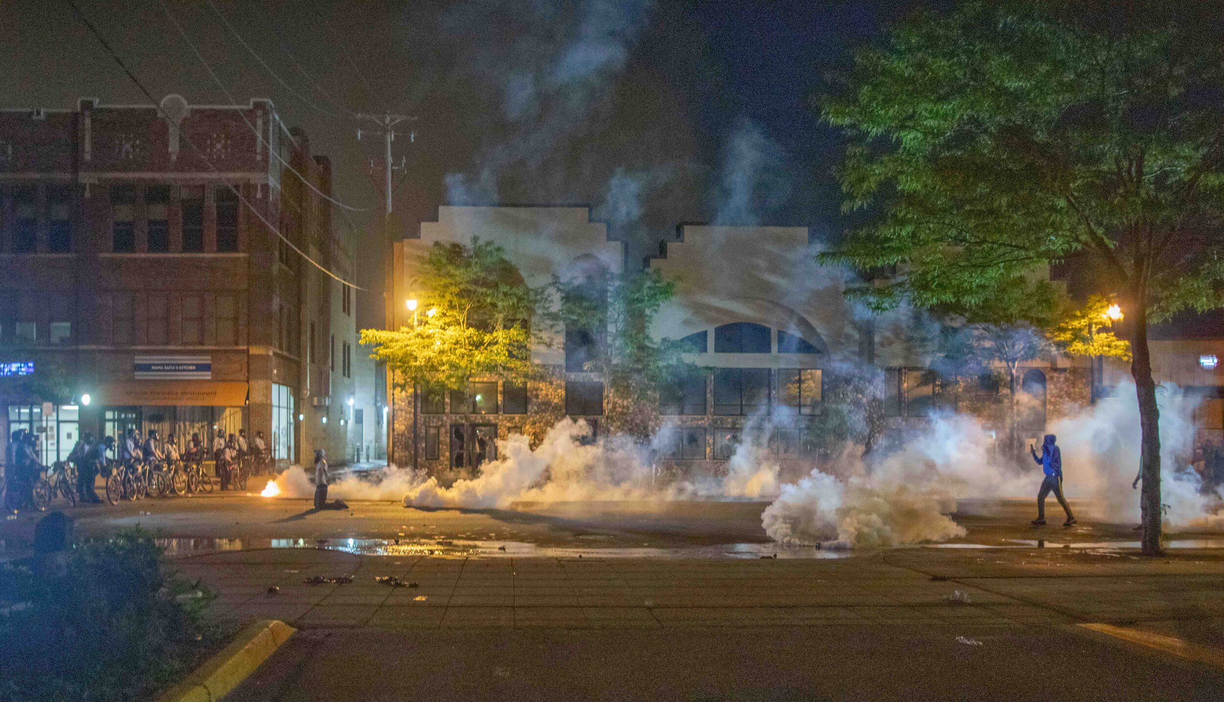  On his knees, a protester holds his arms out as a tear gas canister blows up near him in Minneapolis, Minnesota on May 27. 