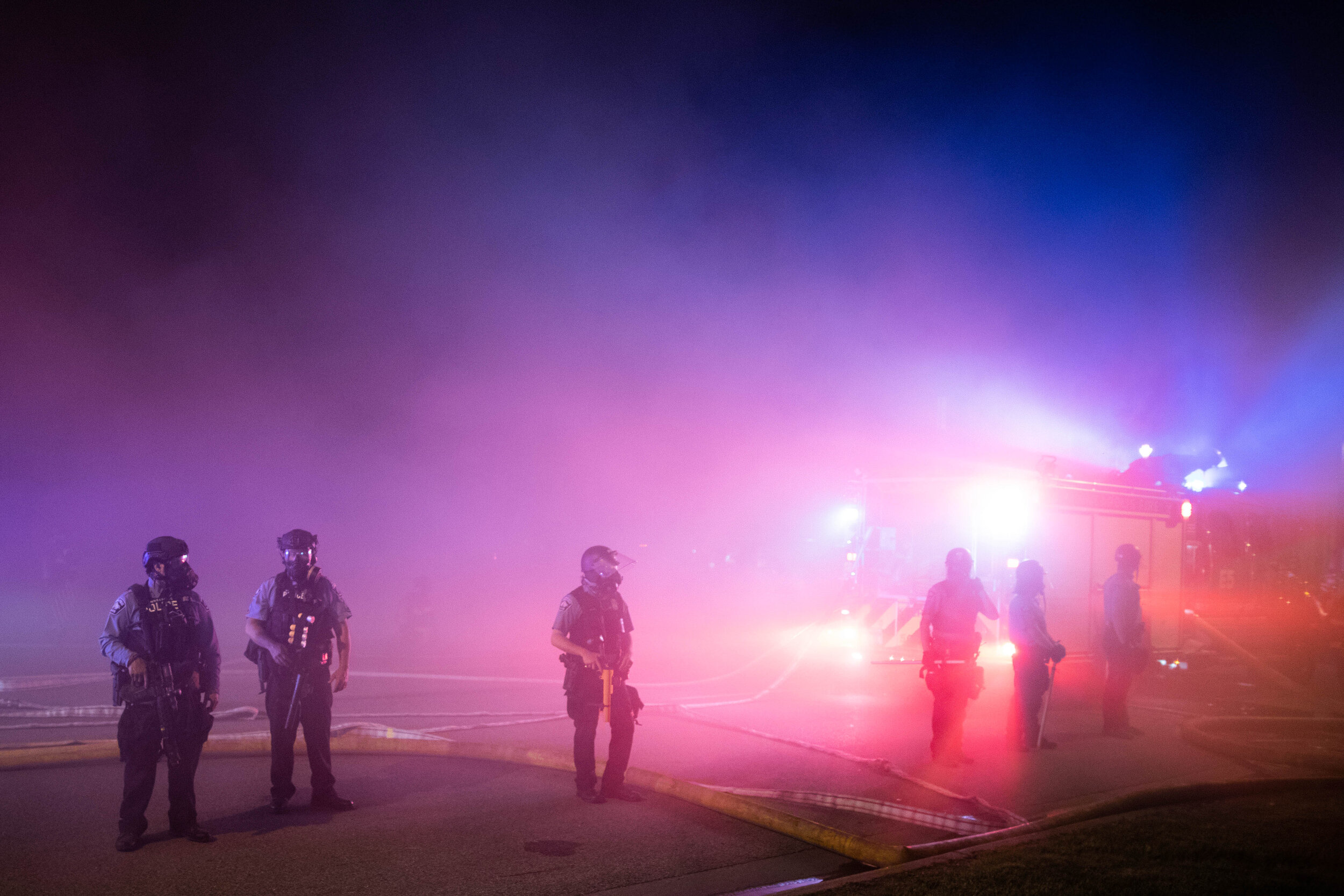  Police guard firefighters as they extinguish a fire set during a riot over the police killing of George Floyd in Minneapolis, Minnesota on May 28. 