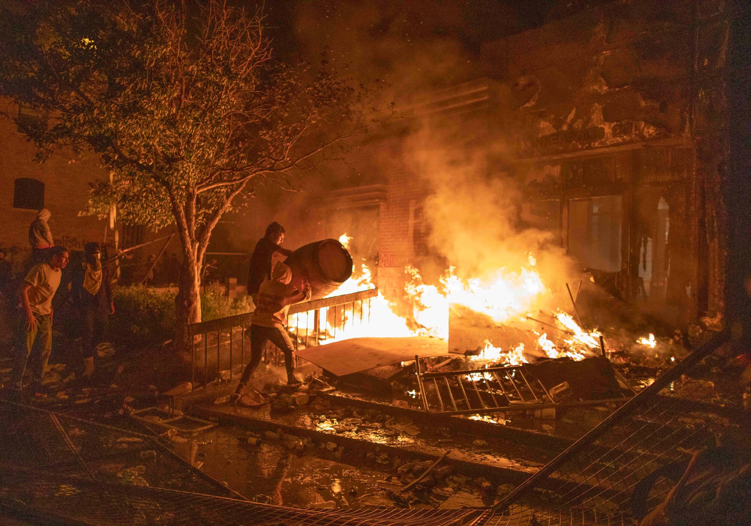  Protesters move a wooden cask together into a fire in an attempt to burn down the Minneapolis 3rd police precinct after riots broke out all over the Twin Cities over the police killing of George Floyd on May 28, 2020. 