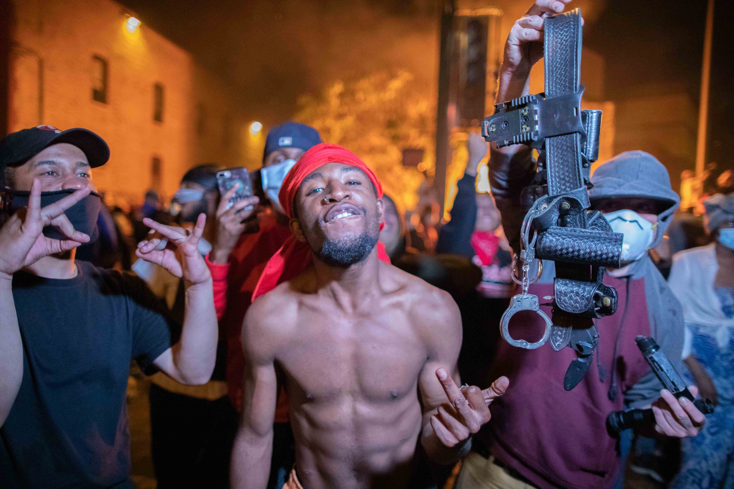  As the 3rd police precinct in Minneapolis, Minnesota burns behind him a protester and his friend proudly hold up a police belt during a riot over the killing of George Floyd on May 28. 