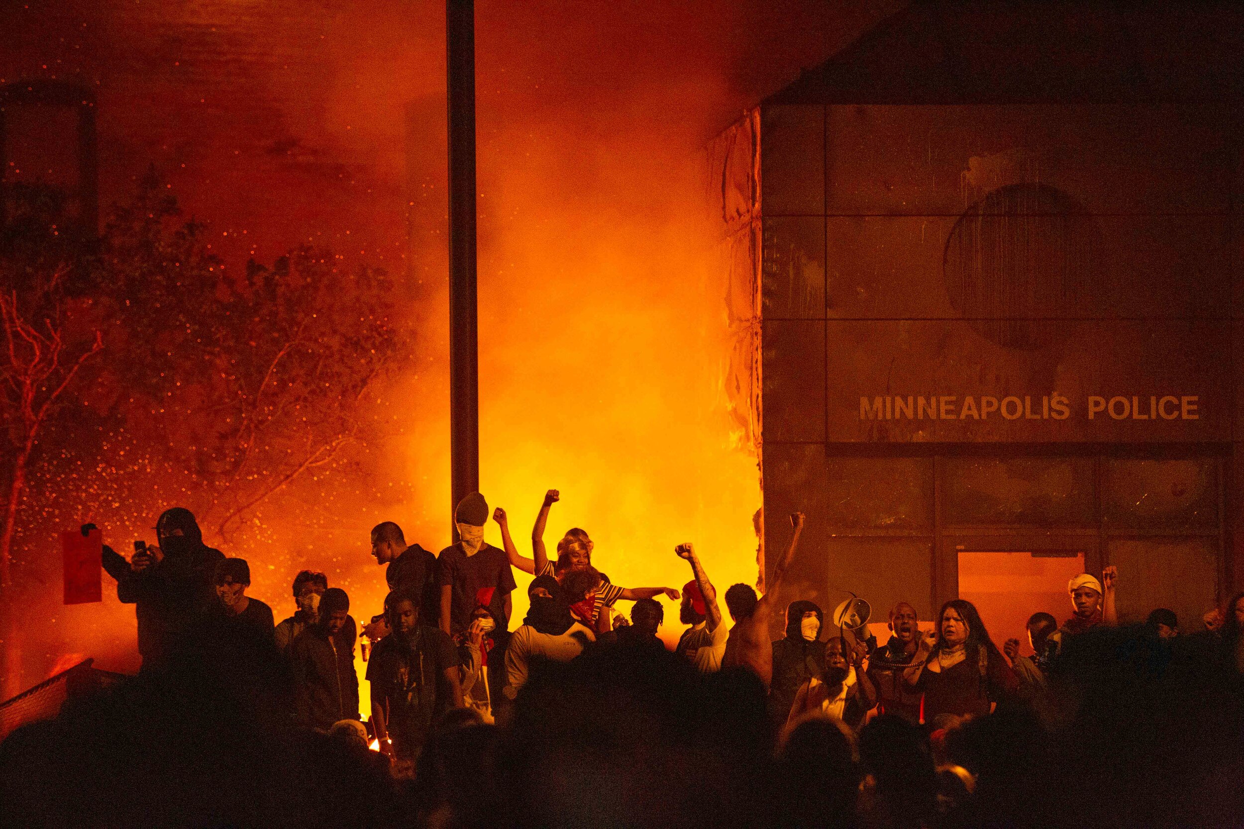  Protesters raise their fists as the 3rd police precinct burns in Minneapolis, Minnesota behind them during a riot over the killing of George Floyd on May 28, 2020. 