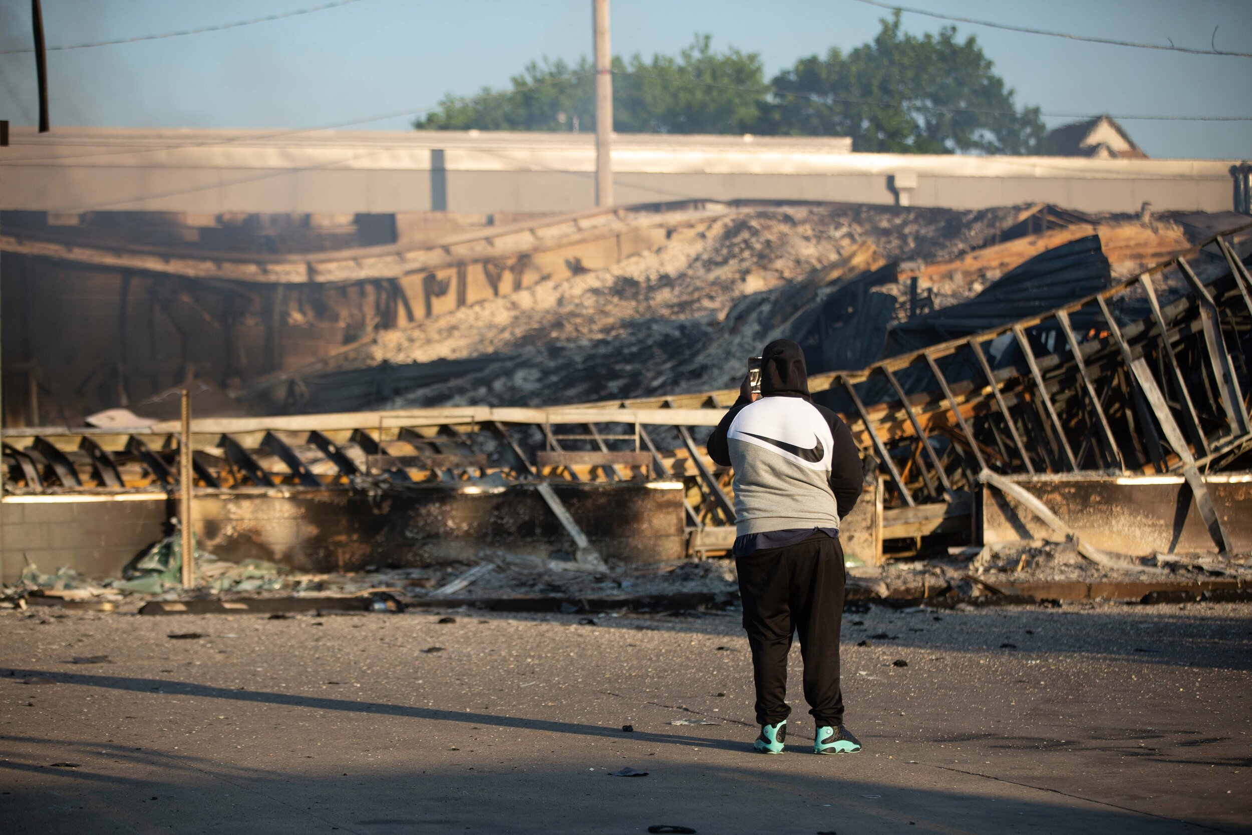  A man takes a video on his cell phone of a Auto Zone that burned down on Lake Street in Minneapolis, Minnesota during a riot over the police killing of Geoge Floyd on May 30, 2020. Chris Juhn/Zuma. 