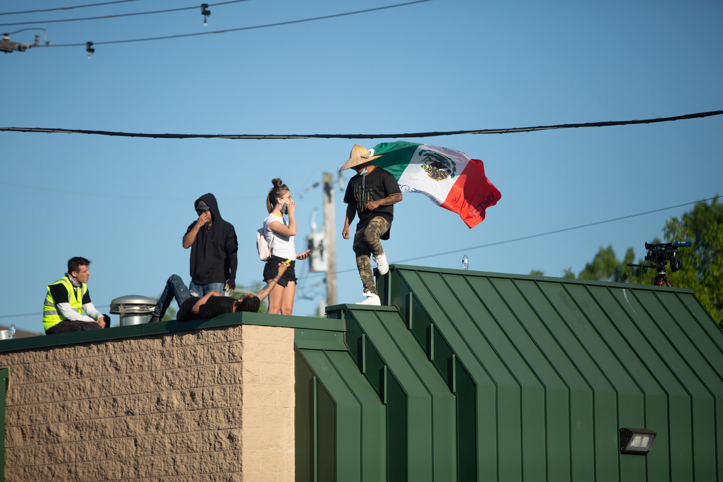  Poretsters stand on the roof of a strip mall that was looted the previous night during a protest over the police killing of George Floyd in Minneapolis, Minnesota on May 30, 2020. Chris Juhn/Zuma 