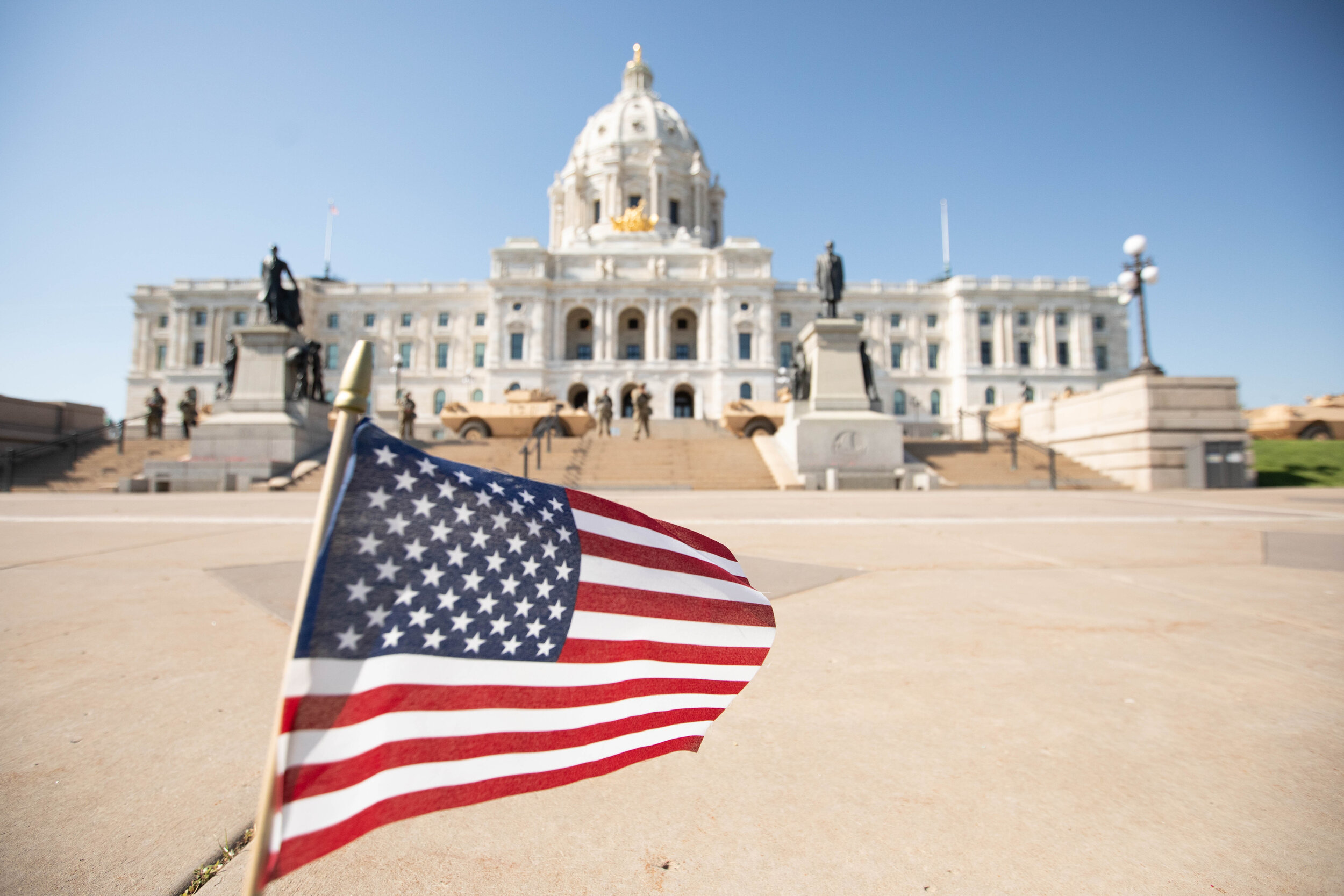  An American flag waves at the end of the lawn of the State Capitol building in Saint Paul, Minnesota as the National Guard secure the steps with armored vehicles and armed soldiers on June 1, 2020. Chris Juhn/Zenger 