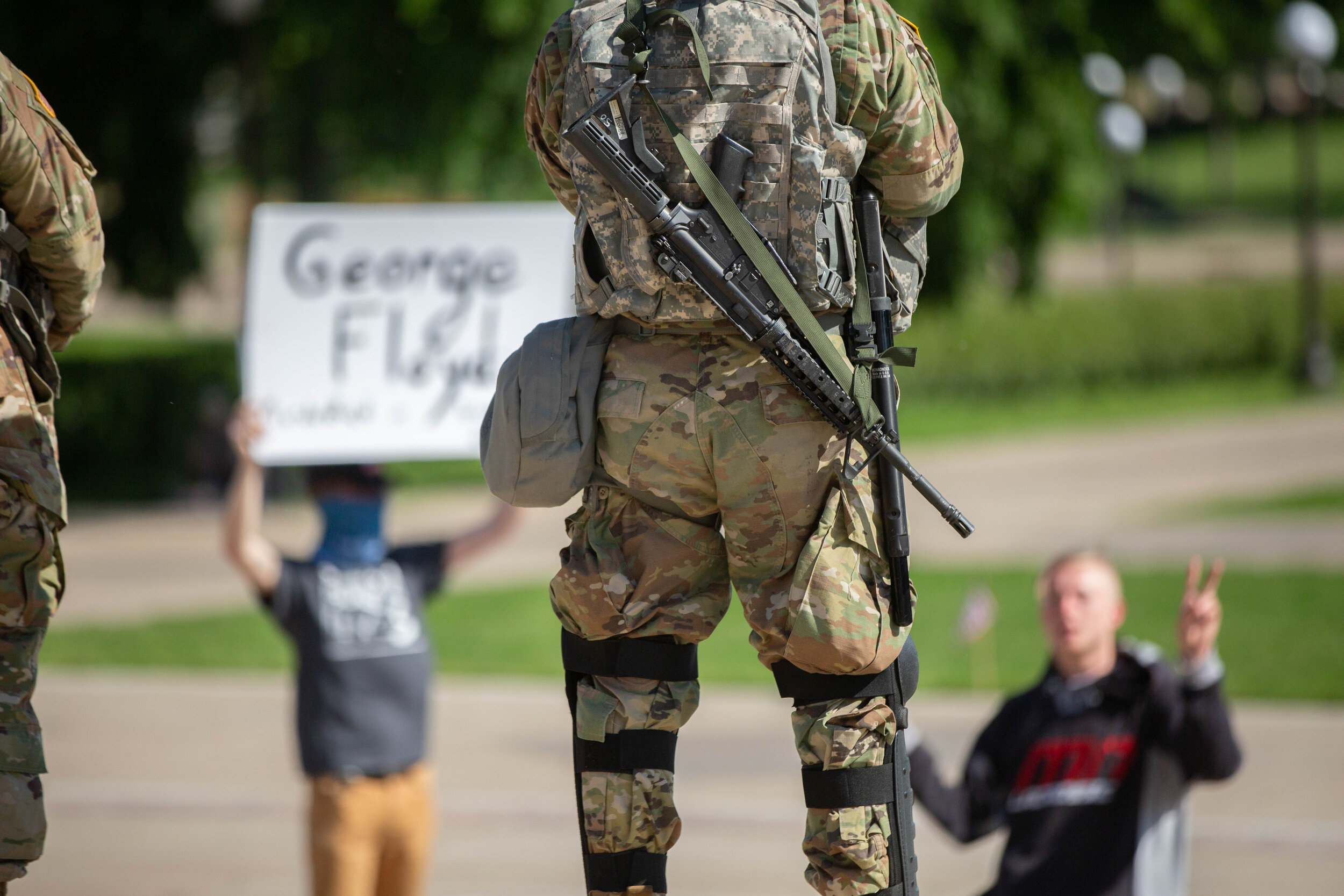  Two men peacefully protest at the bottom of the State Capitol building in Saint Paul, Minnesota. A National Guard soldier sits in front of them with a gun on his back on June 1, 2020. Chris Juhn/Zenger 