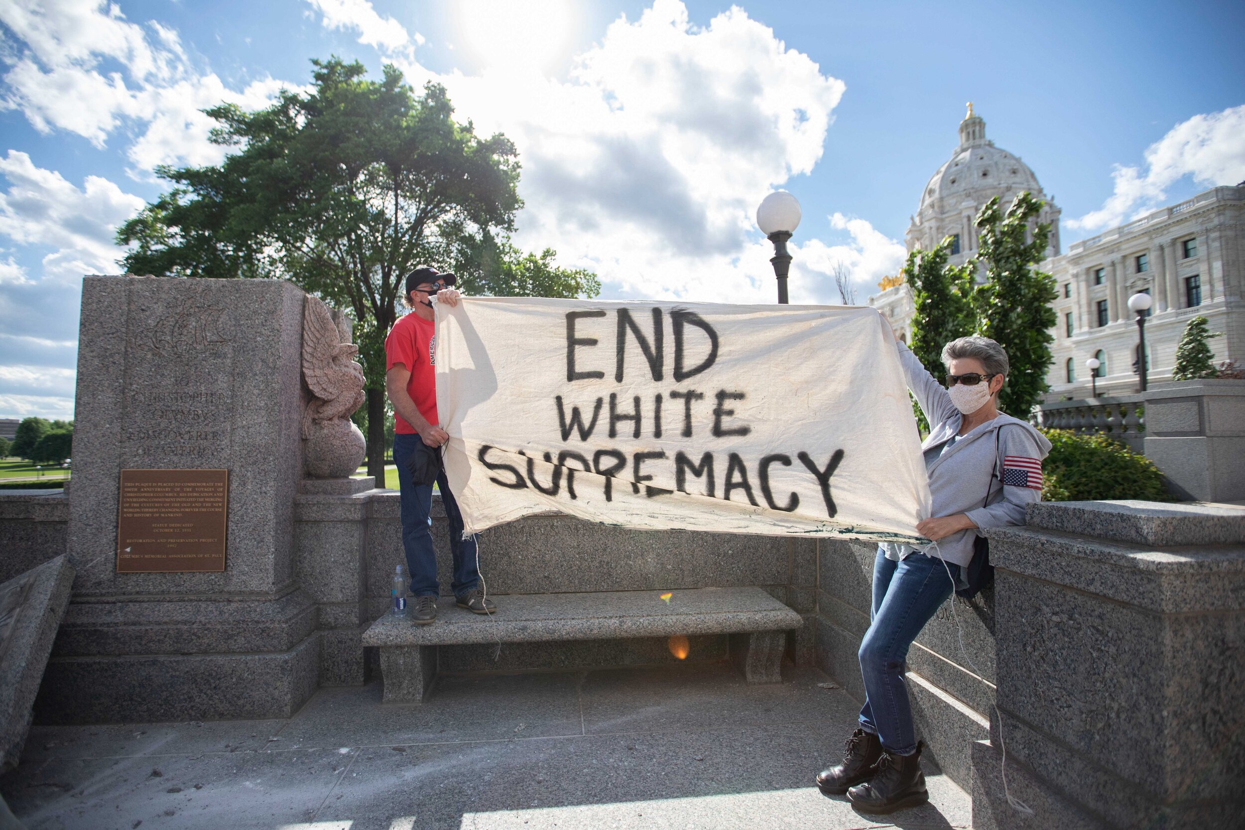  Rachel Goligoski (right) holds up a banner at the site where the Chistopher Columbus statue was torn down in Saint Paul, Minnesota on Jun 10, 2020. 