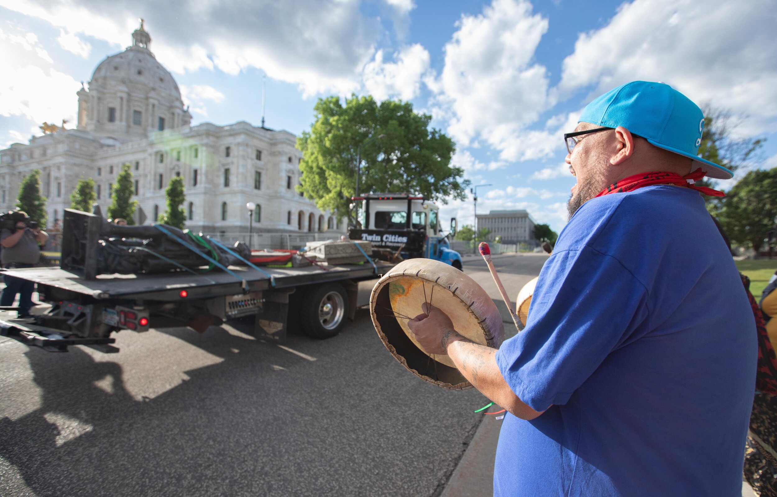  Native American activists beat drums and chant as the statue of Christopher Columbus goes by on a flatbed after it was torn down on the grounds of the State Capitol on Jun 10, 2020. 