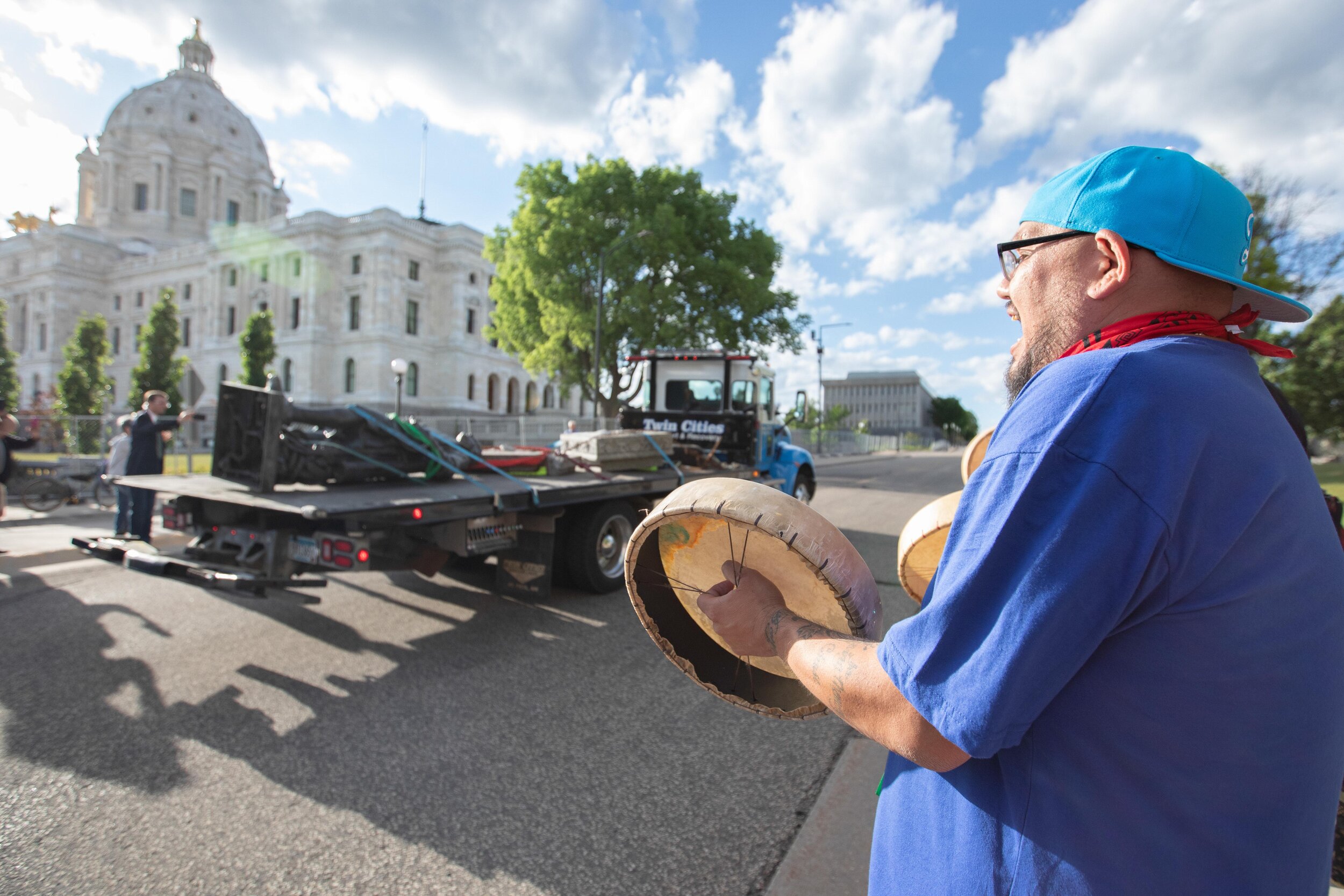  Native American activists beat drums and chant as the statue of Christopher Columbus goes by on a flatbed after it was torn down on the grounds of the State Capitol on Jun 10, 2020. 
