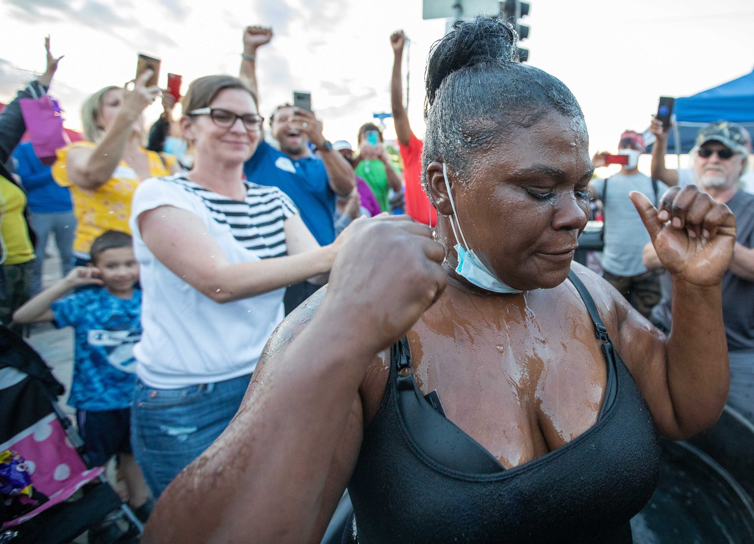  After being baptised a women pauses as community memebers cheer behind her at the George Floyd memorial in Minneapolis, Minnesota on Jun 13, 2020., 2020. 