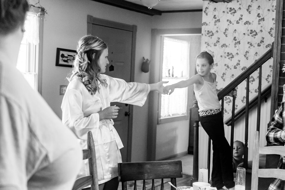 A little girl reaches out to a bride to encourage her to get ready faster 