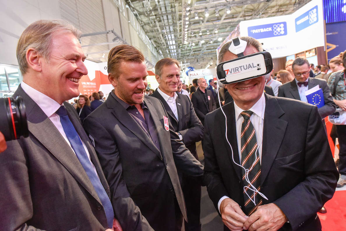 Oettinger (hier rechts im Bild. Aber NICHT der Kerl mit der Europa-Mappe. Sondern mit der Virtual Reality Brille auf dem Kopf. Quelle: dmexco.de)